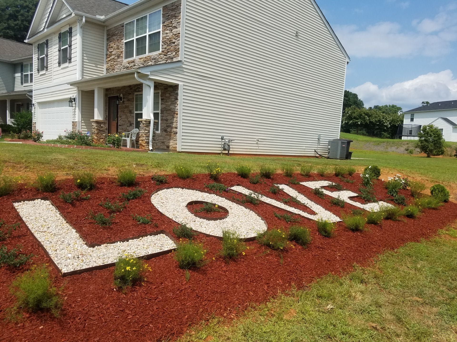 The word love is written in gravel in front of a house.