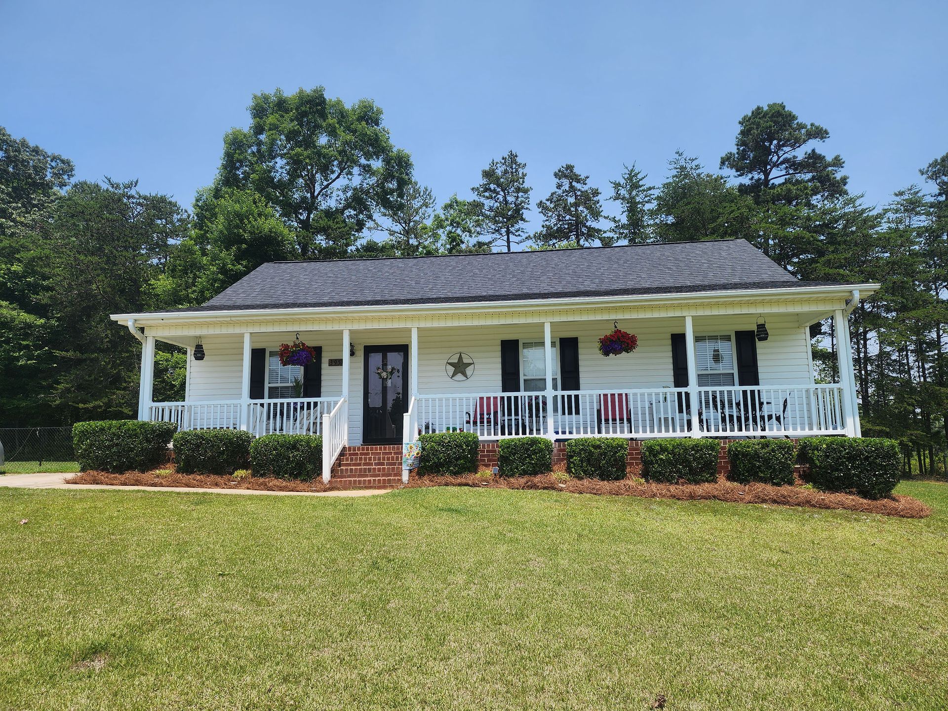 A white house with a porch and trees in the background