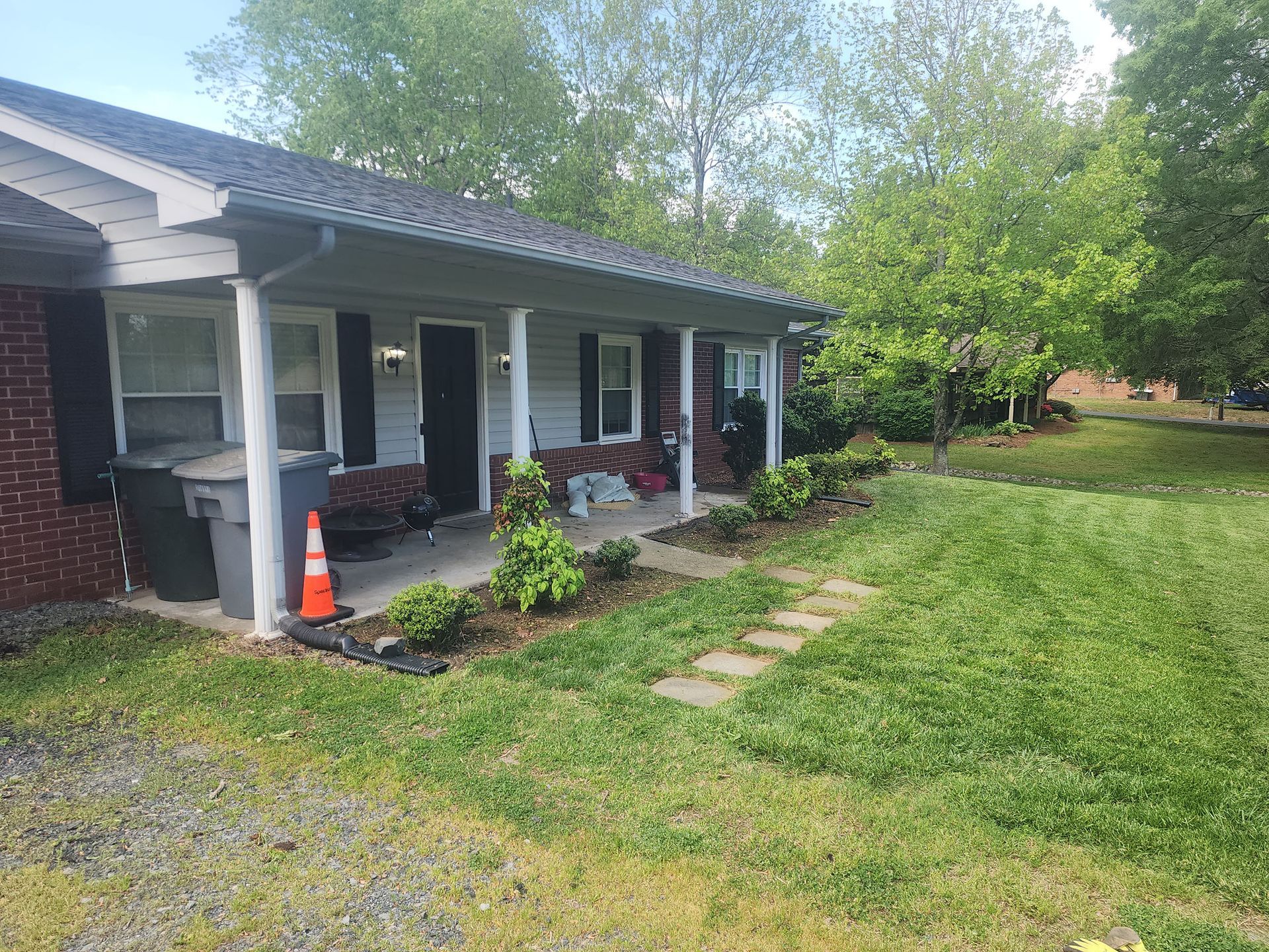 A brick house with a porch and a walkway in front of it.
