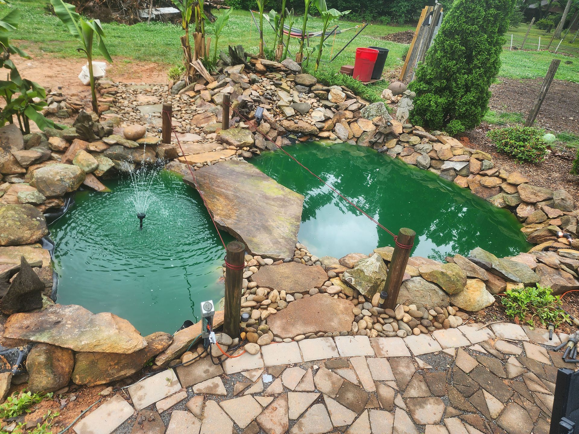 A pond with a fountain in the middle of it surrounded by rocks.