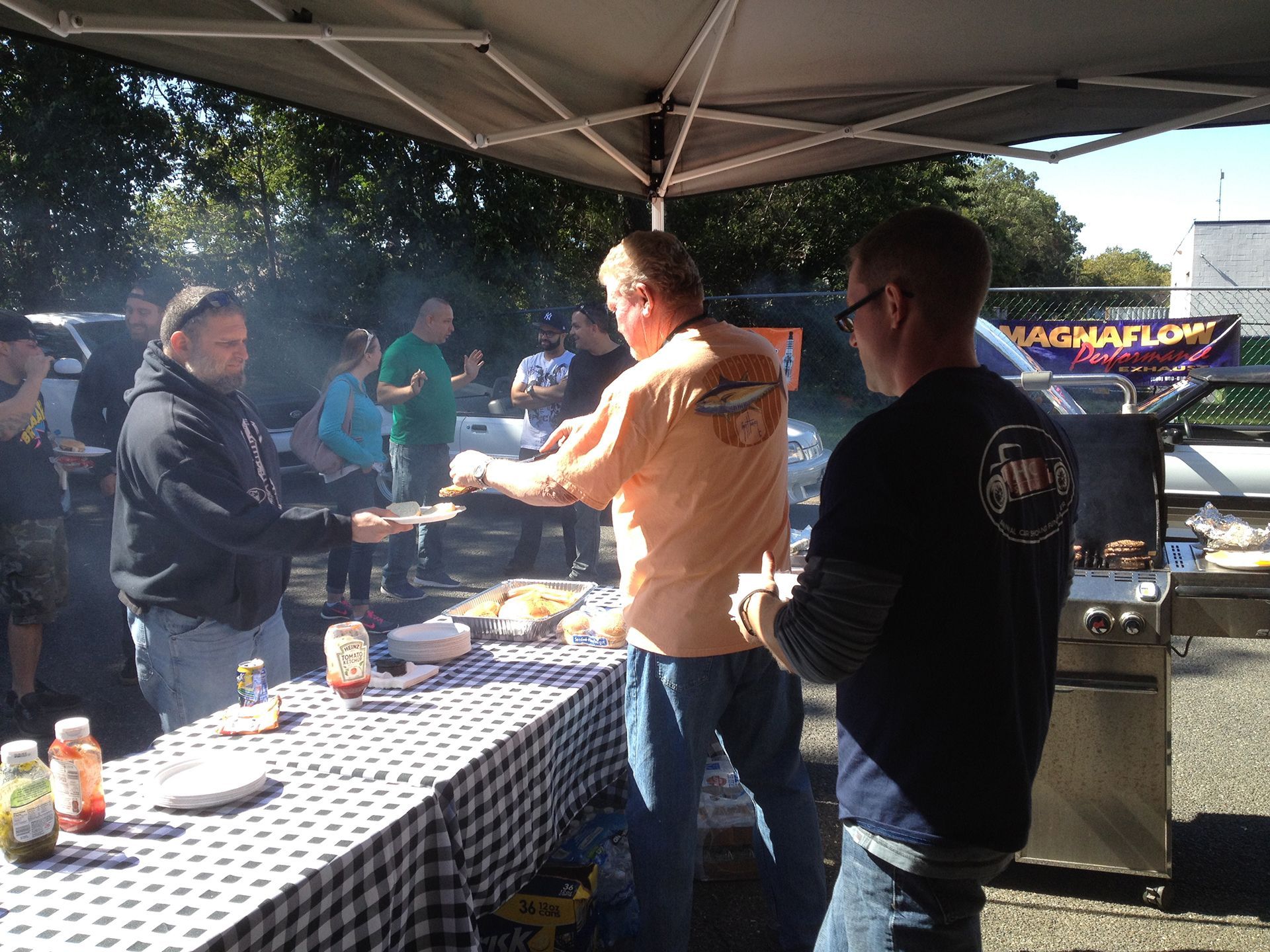 A group of men standing around a table with a sign that says magnaflow in the background