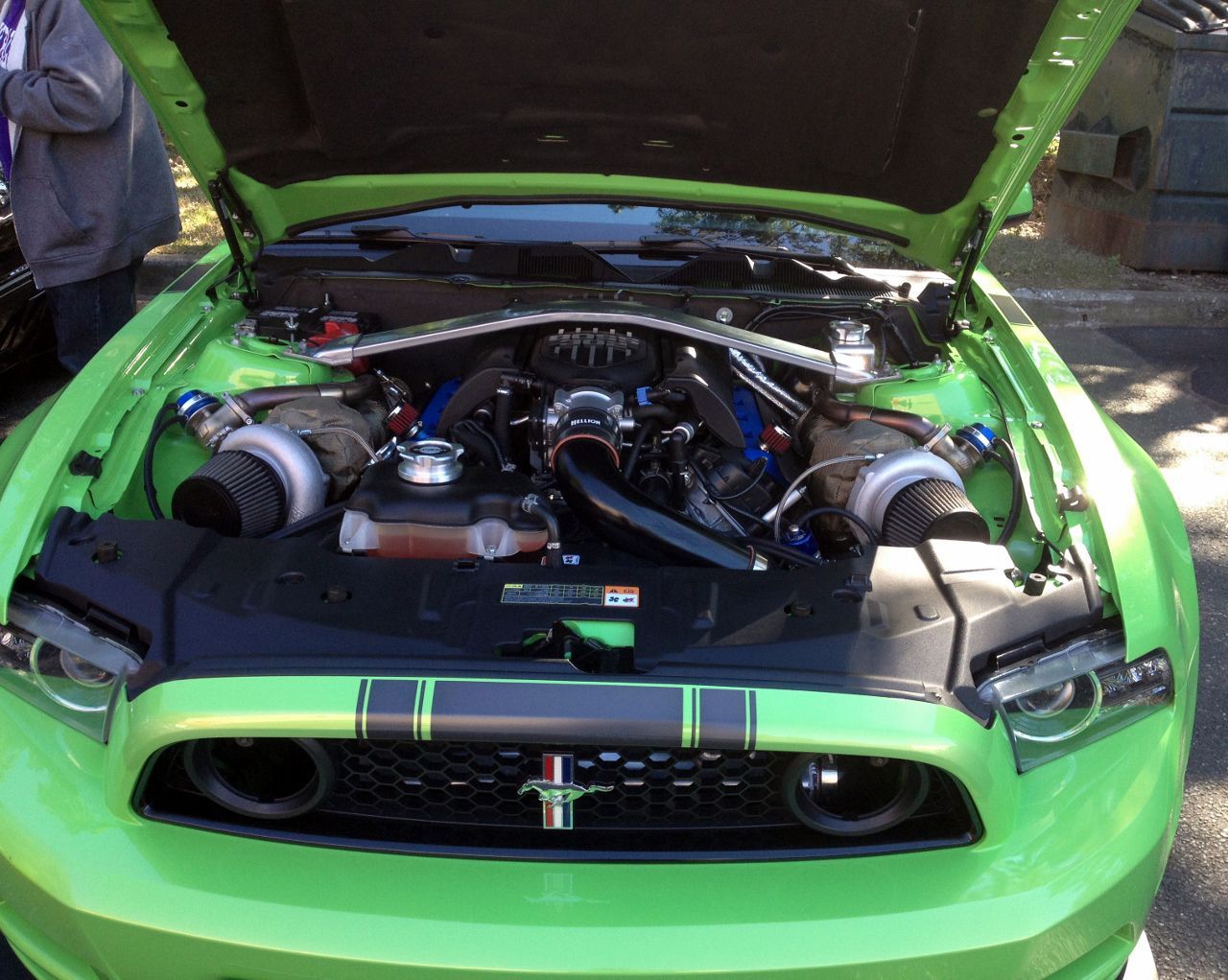 The engine of a green mustang with the hood open
