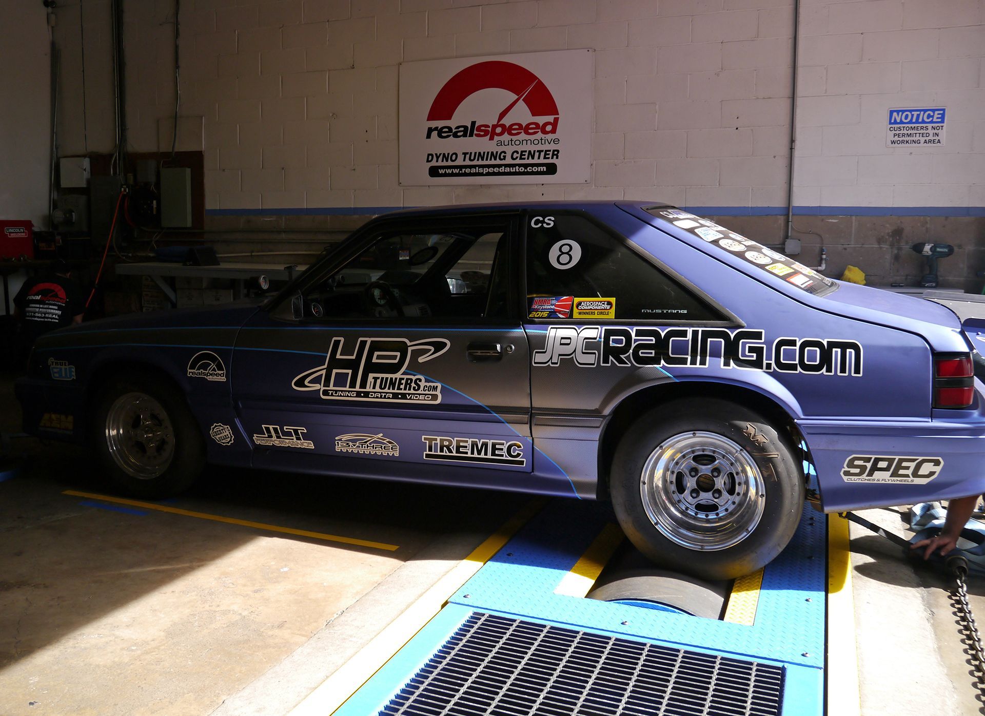 A blue racing car is parked in a garage