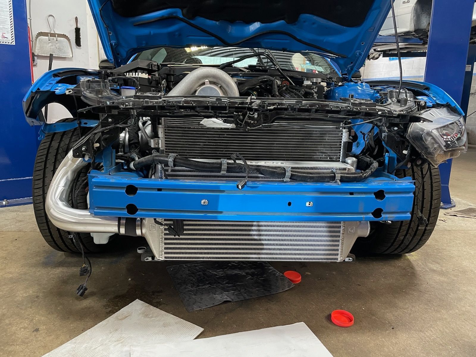 Blue car with open hood; front end exposed with an intercooler and piping.