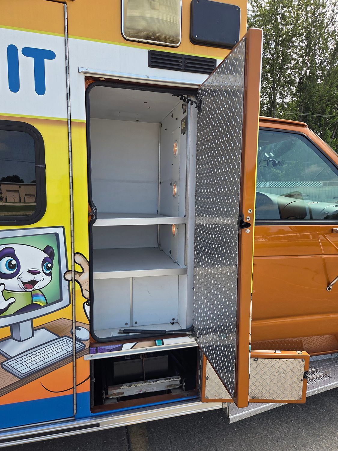 Open storage compartment on colorful ambulance with shelves and a diamond-plate door open to the side