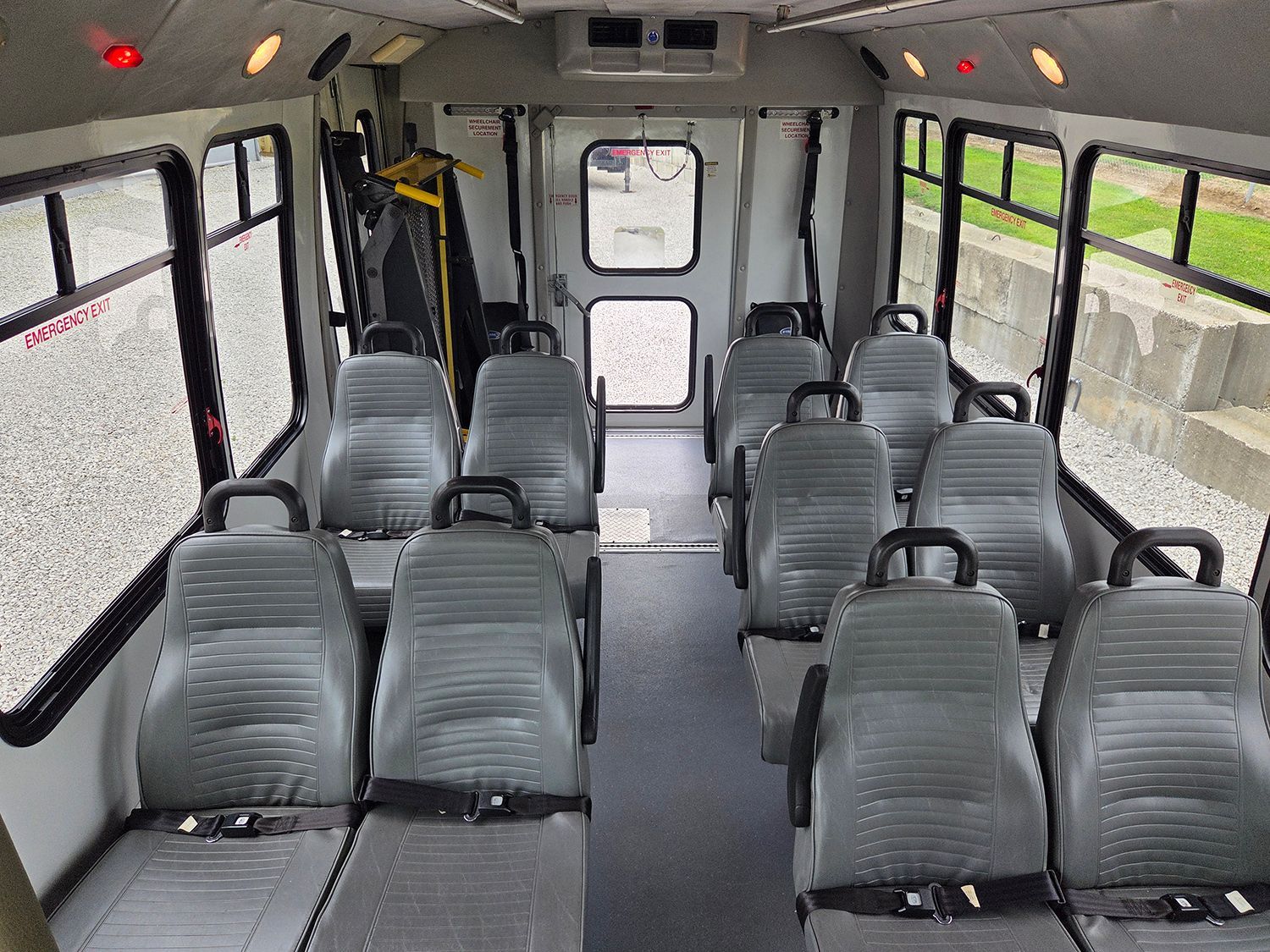 Empty shuttle bus interior with gray seats and large side windows