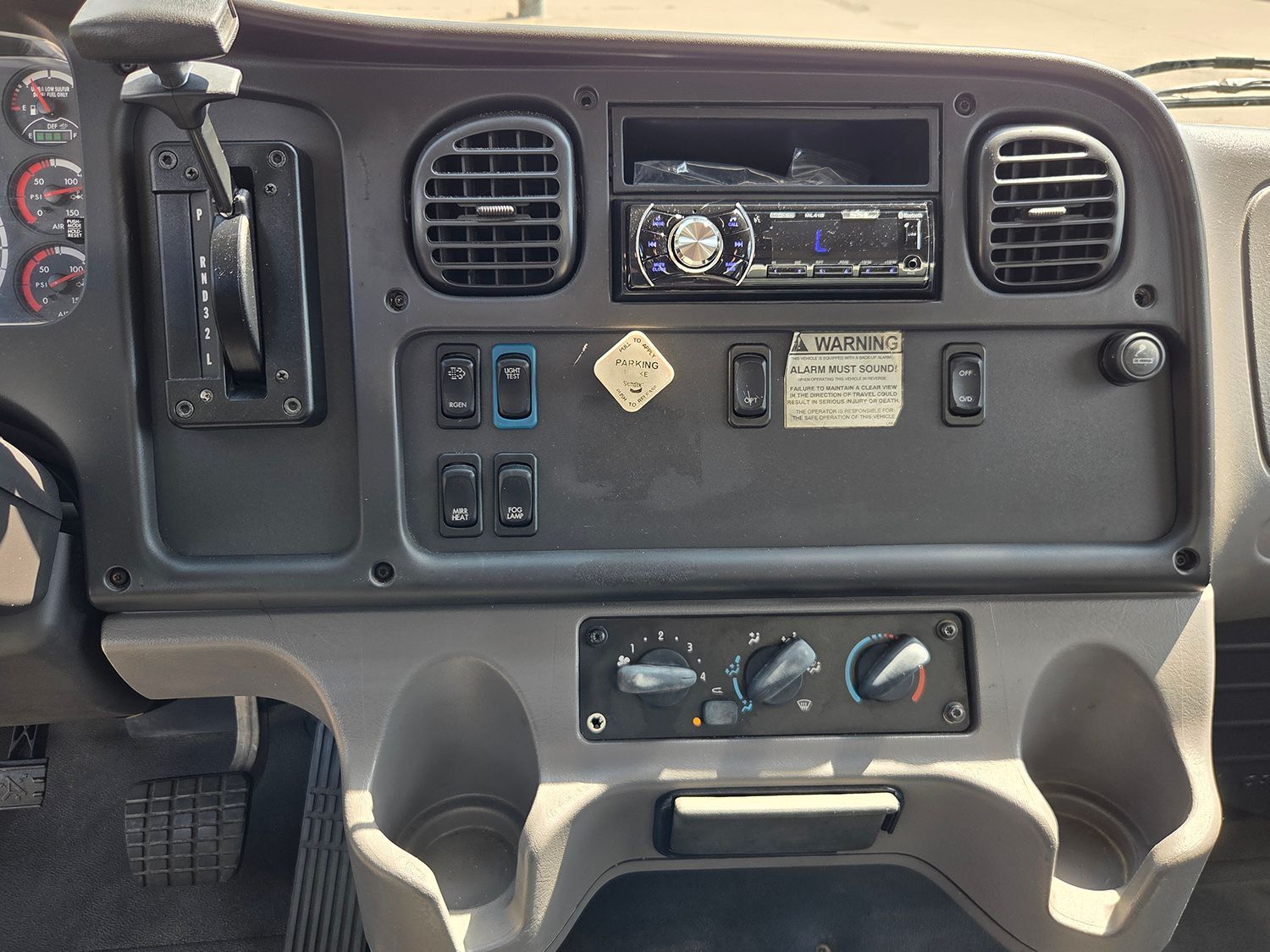 Vehicle dashboard with radio, vents, switches, and cup holders