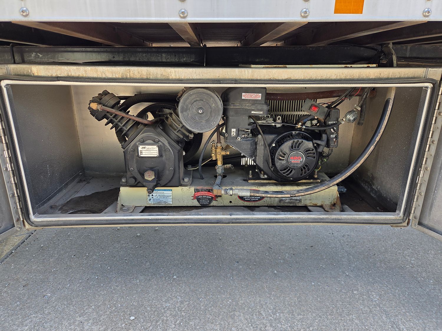 Open equipment compartment with a small engine and mechanical components inside a metal enclosure.