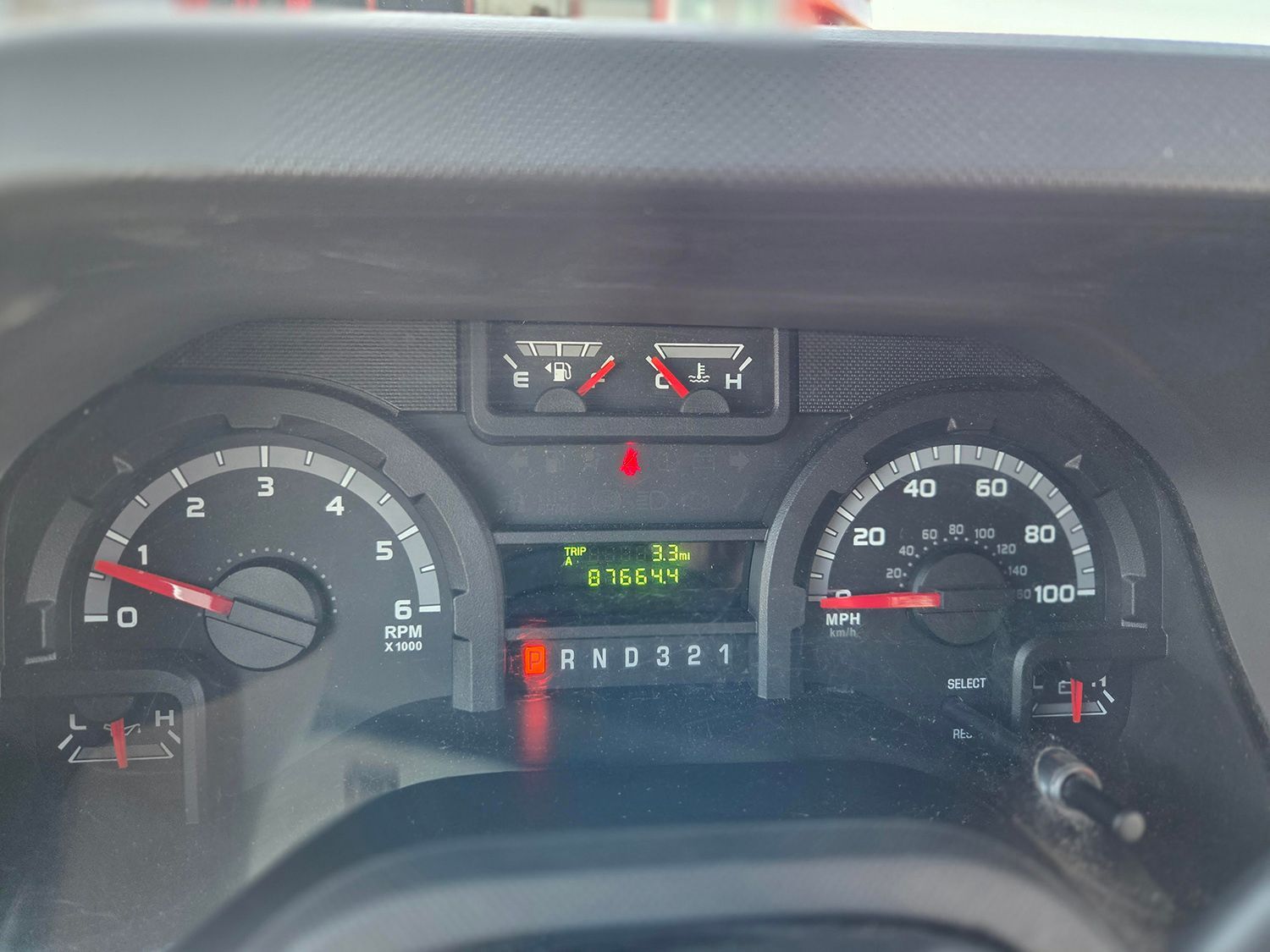Car dashboard with illuminated speedometer, tachometer, and center display showing gear and mileage.