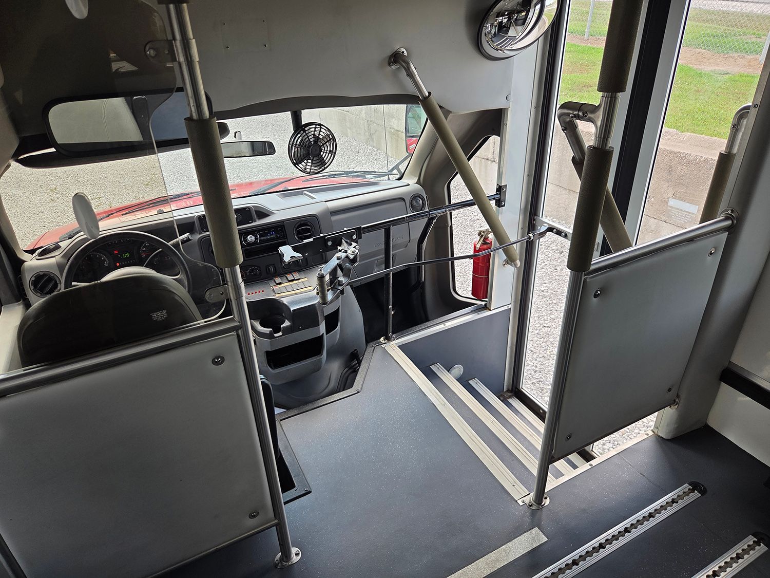 Interior of a bus with empty seats, handrails, and the front windshield view ahead