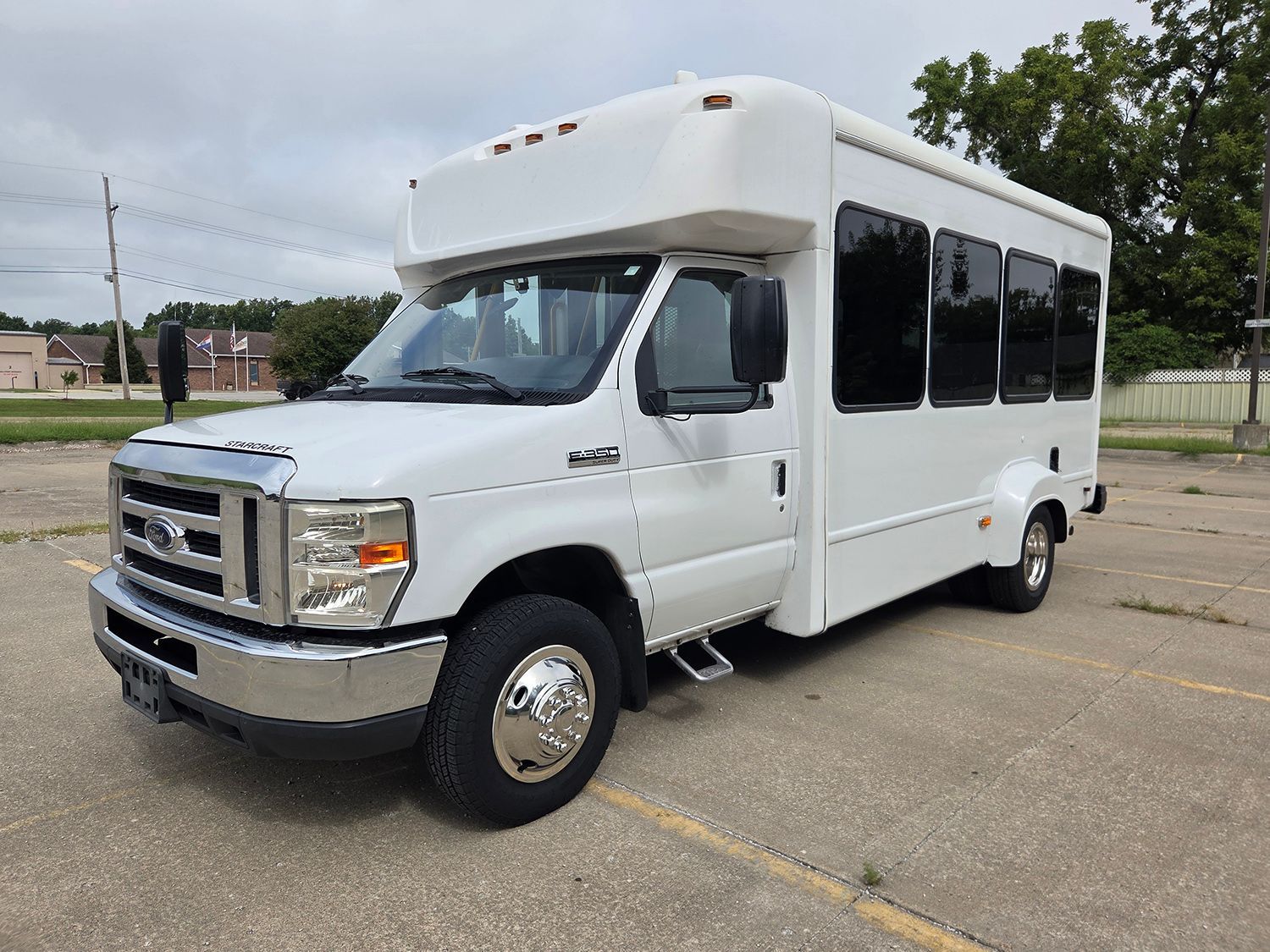 White passenger shuttle bus parked in a lot, shown from the front-left side.
