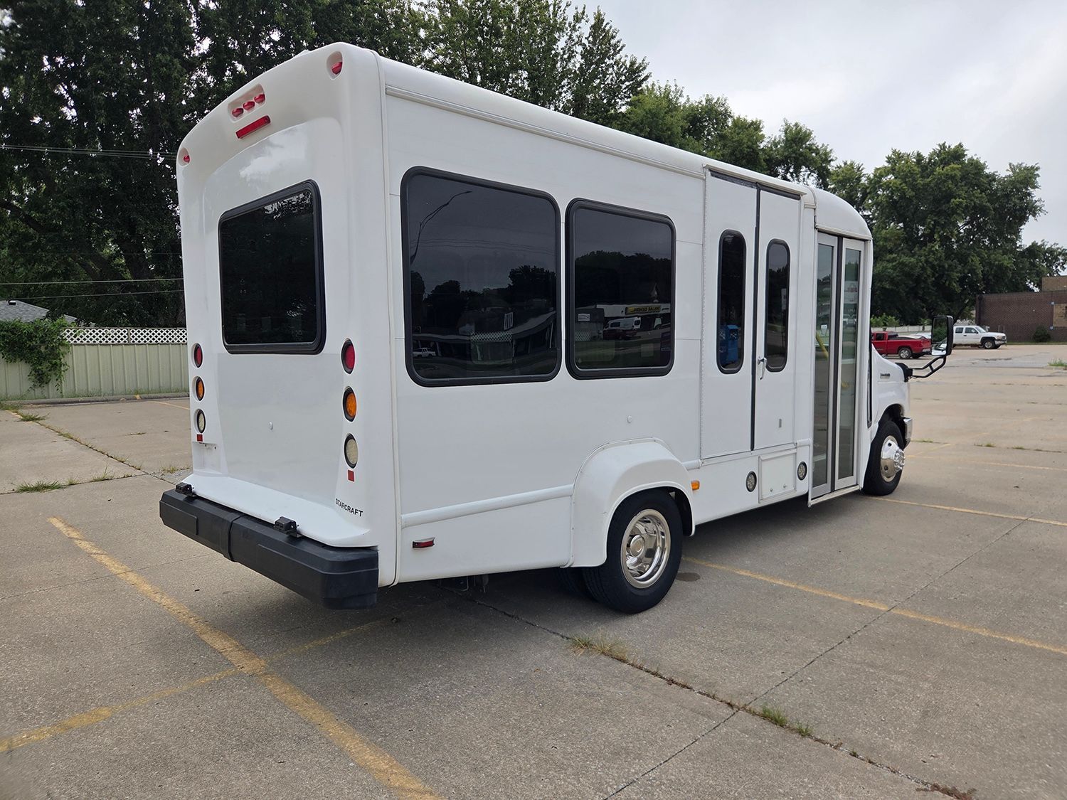White shuttle bus parked in an empty lot, rear-side view.