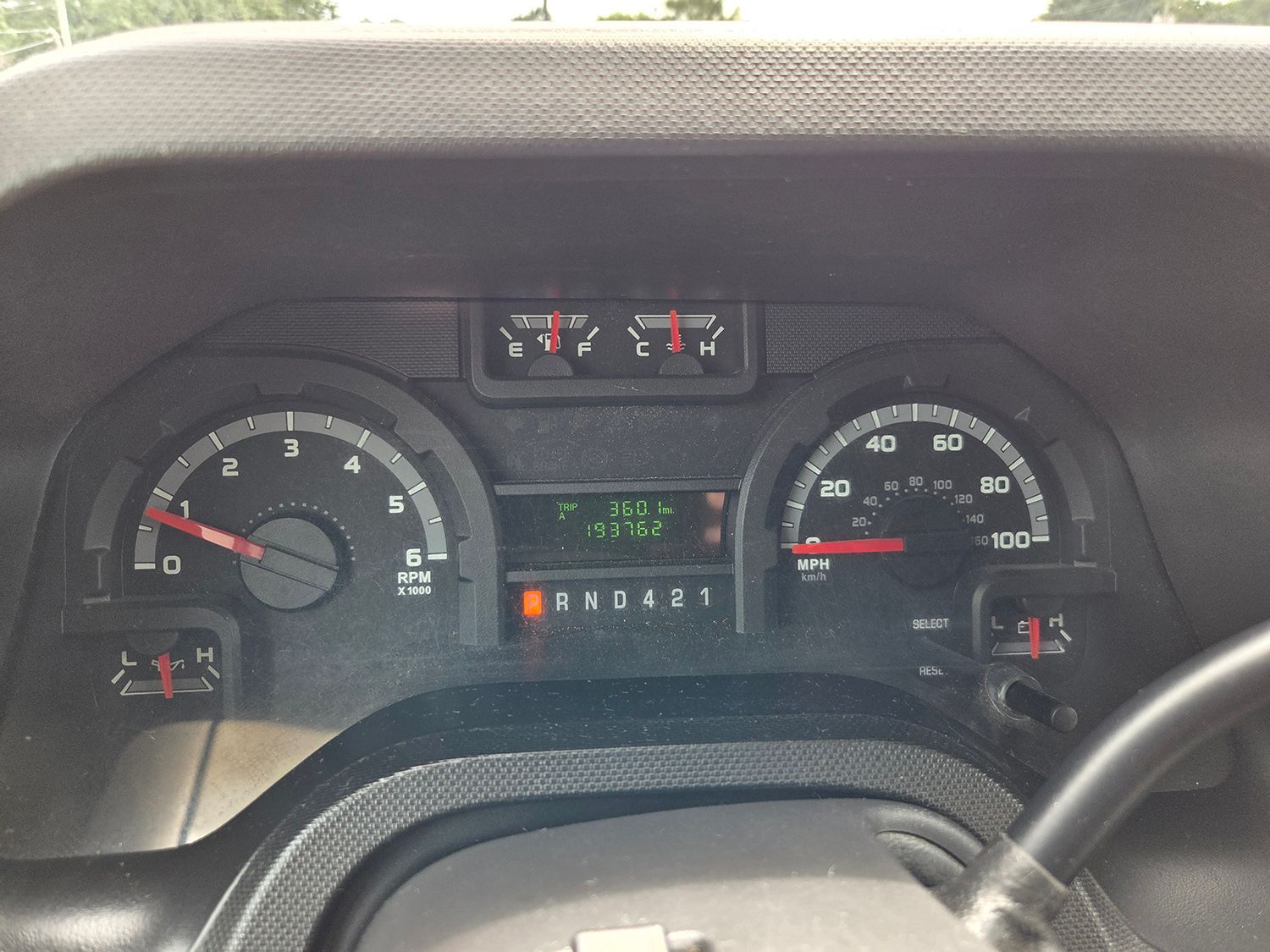 Car dashboard with illuminated gauges and odometer display, viewed from the driver’s seat