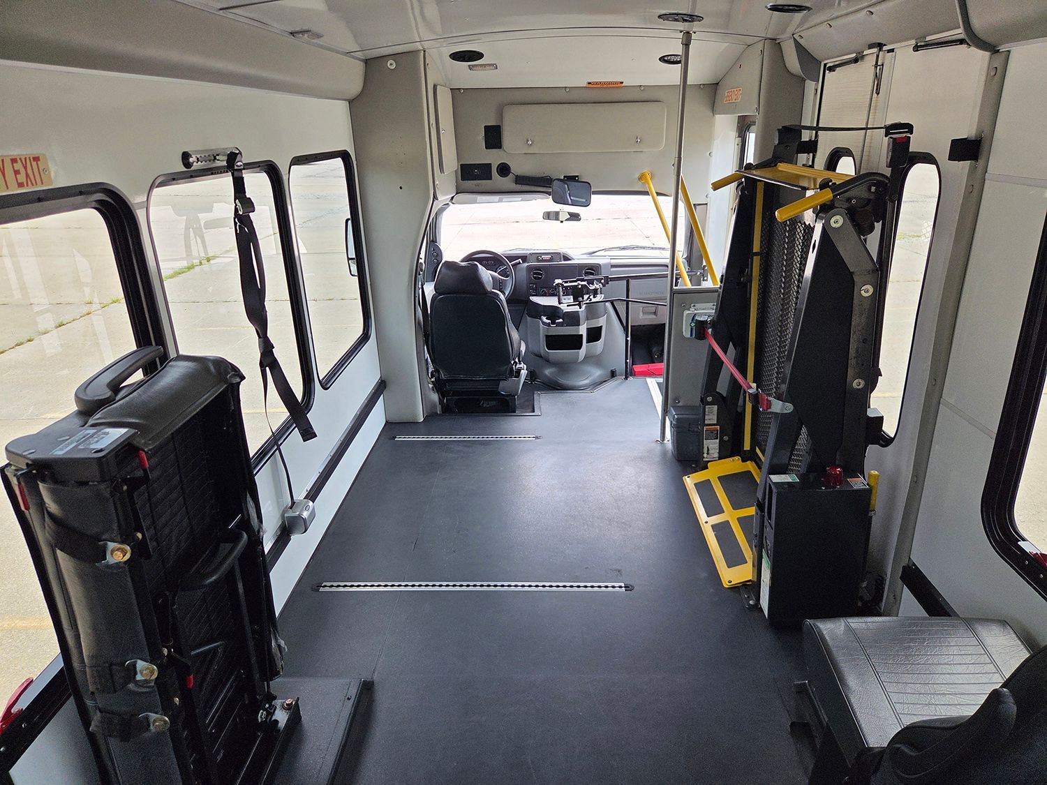 Inside a bus, empty wheelchair-accessible aisle with folded seats and a rear loading area