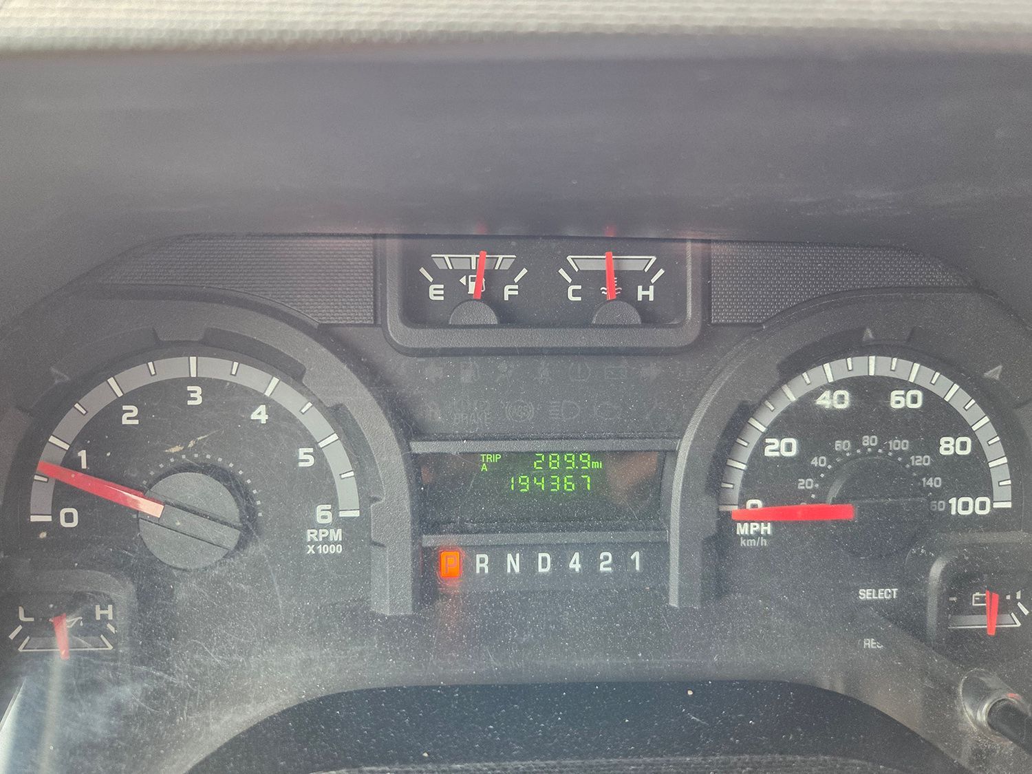 Car dashboard with gauges, warning lights, and gear indicator illuminated.