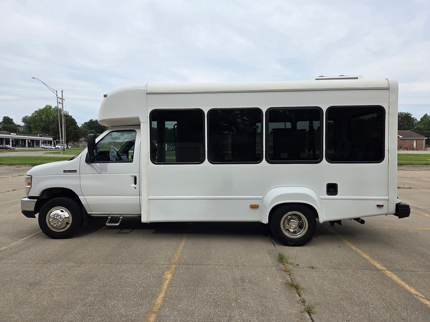 White shuttle bus parked in a lot, side view on a paved roadway.