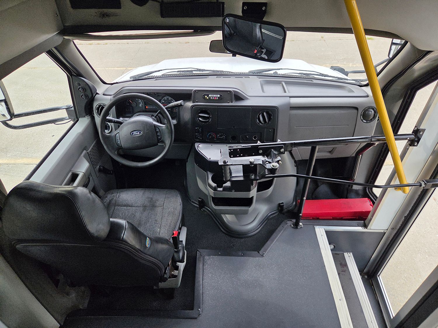 Front interior of a compact vehicle with steering wheel, dashboard, seats, and open side door view