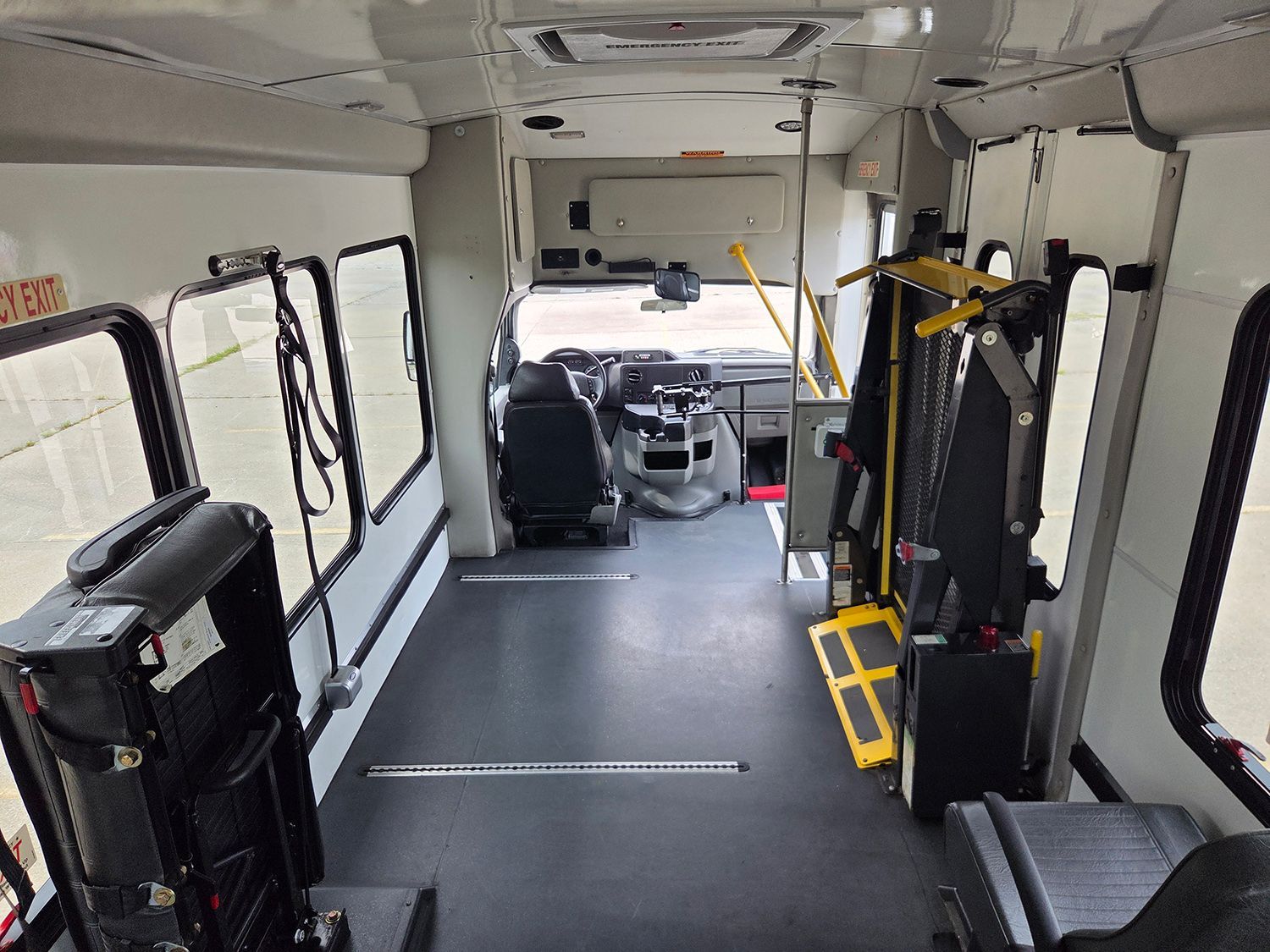 Interior of an empty shuttle bus with wheelchair lift and seats along the sides