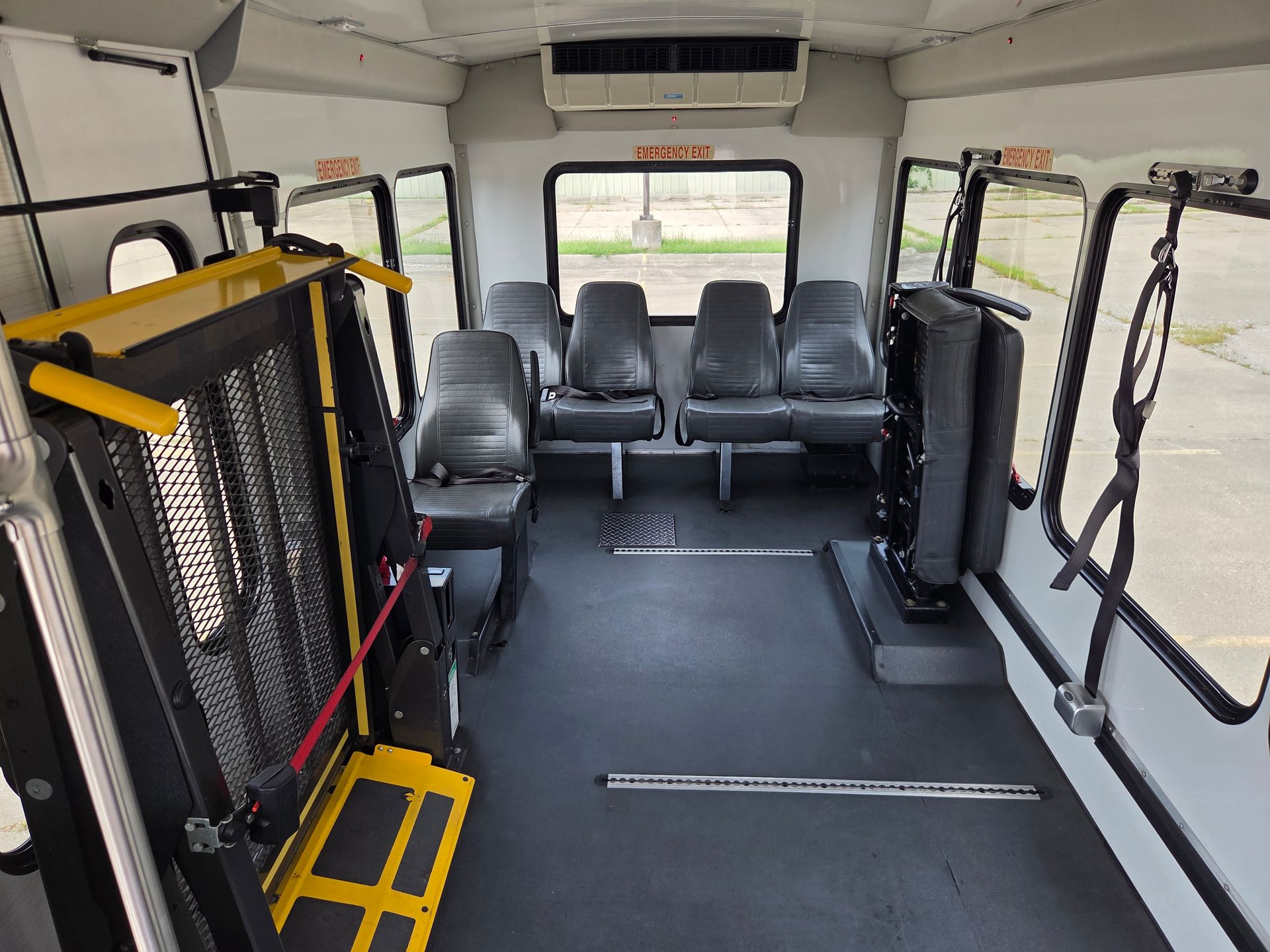 Accessible van interior with folded wheelchair lift, tie-downs, and passenger seats.