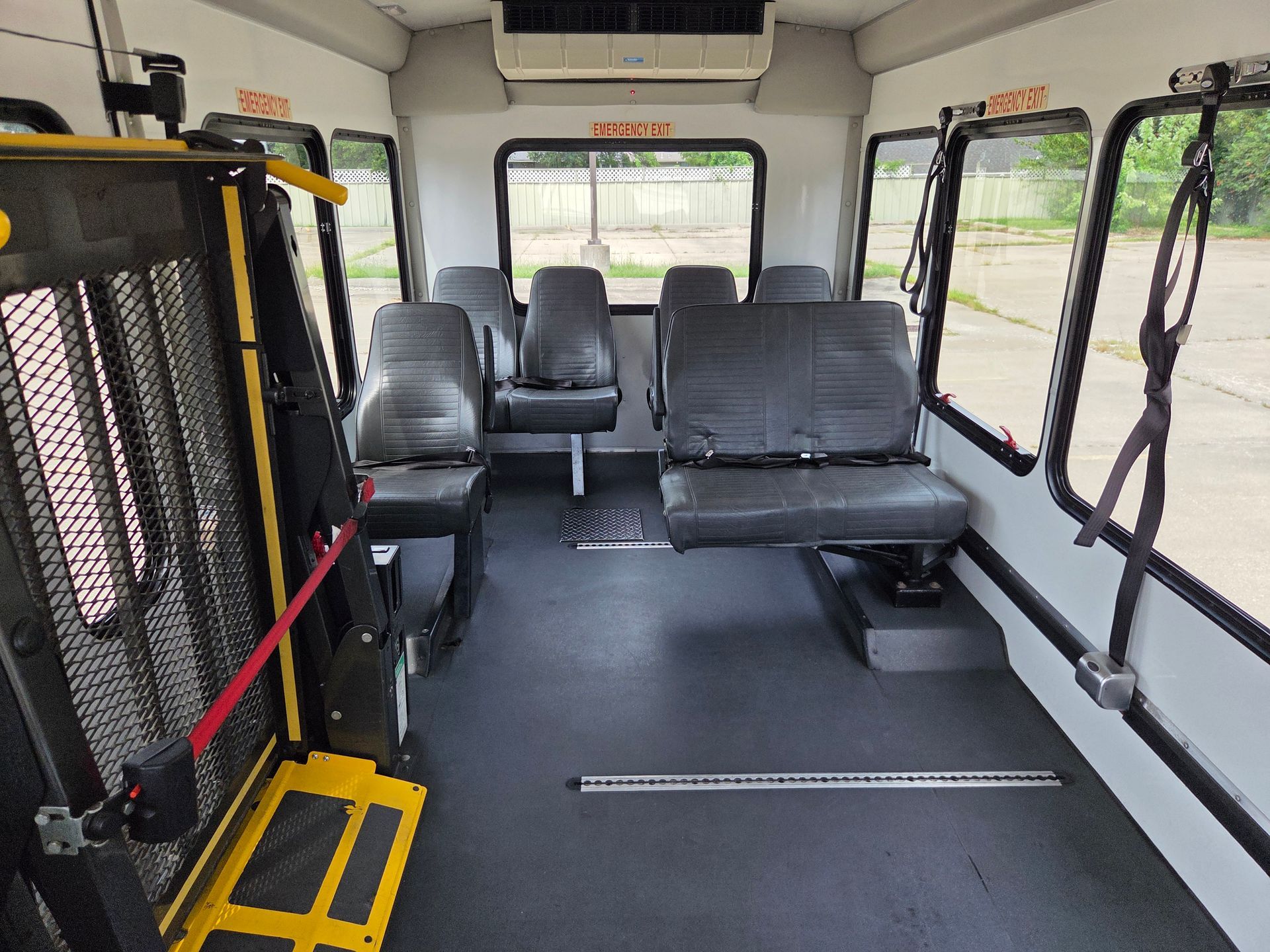 Accessible shuttle bus interior with black seats, white walls, and a rear window view.