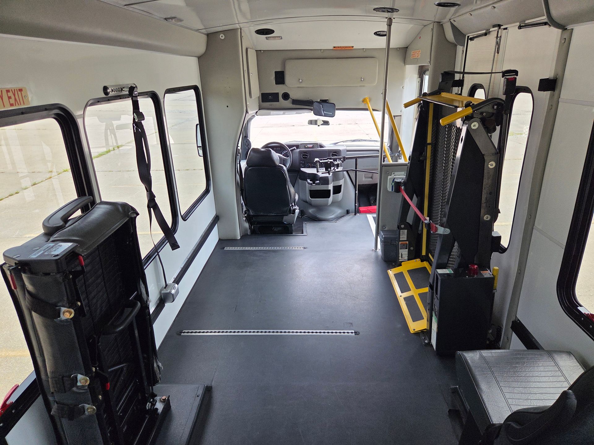 Interior of an empty shuttle bus with black seats and a wheelchair lift near the front