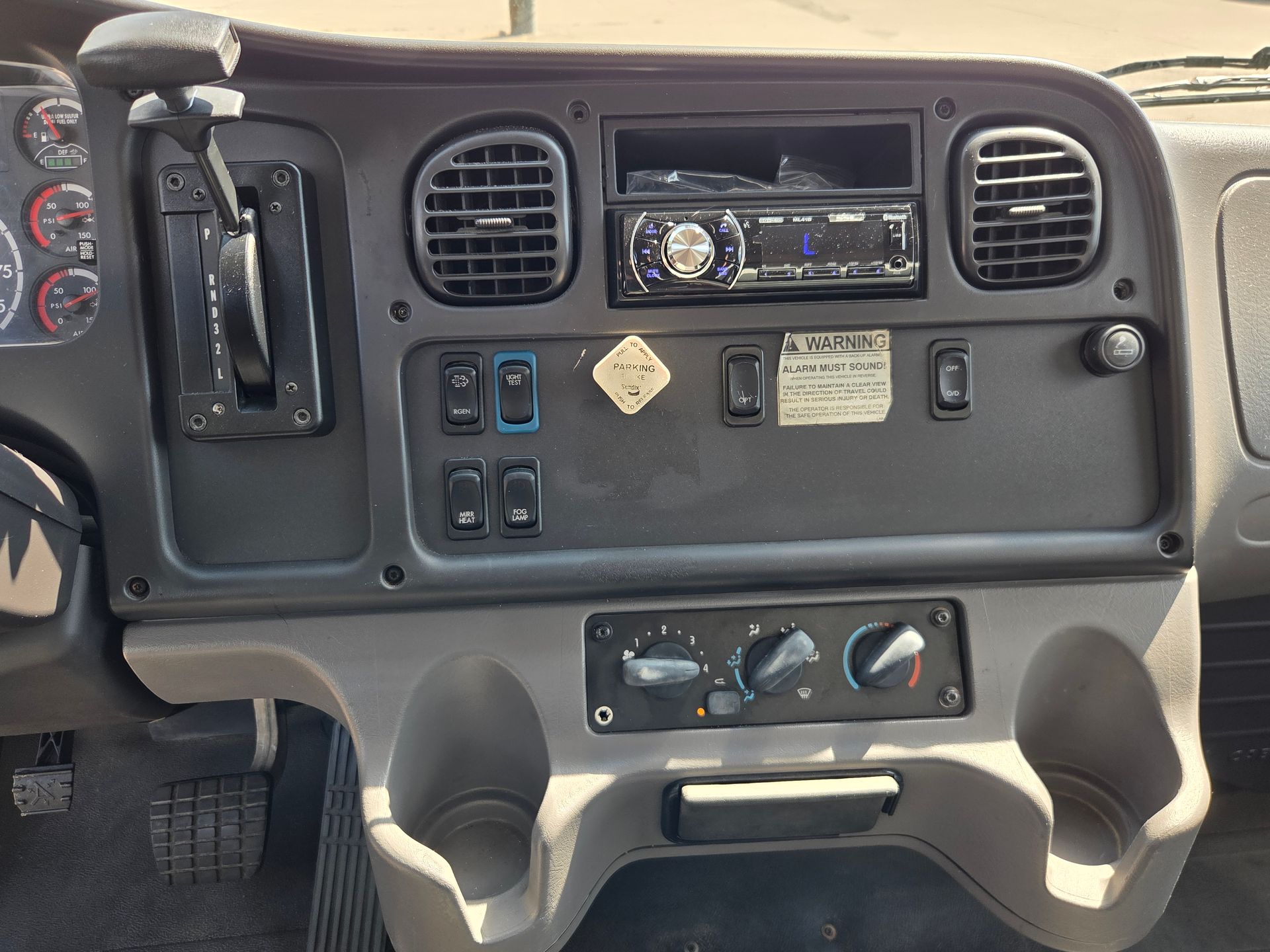 Truck dashboard with radio, vents, switches, cup holders, and storage compartments