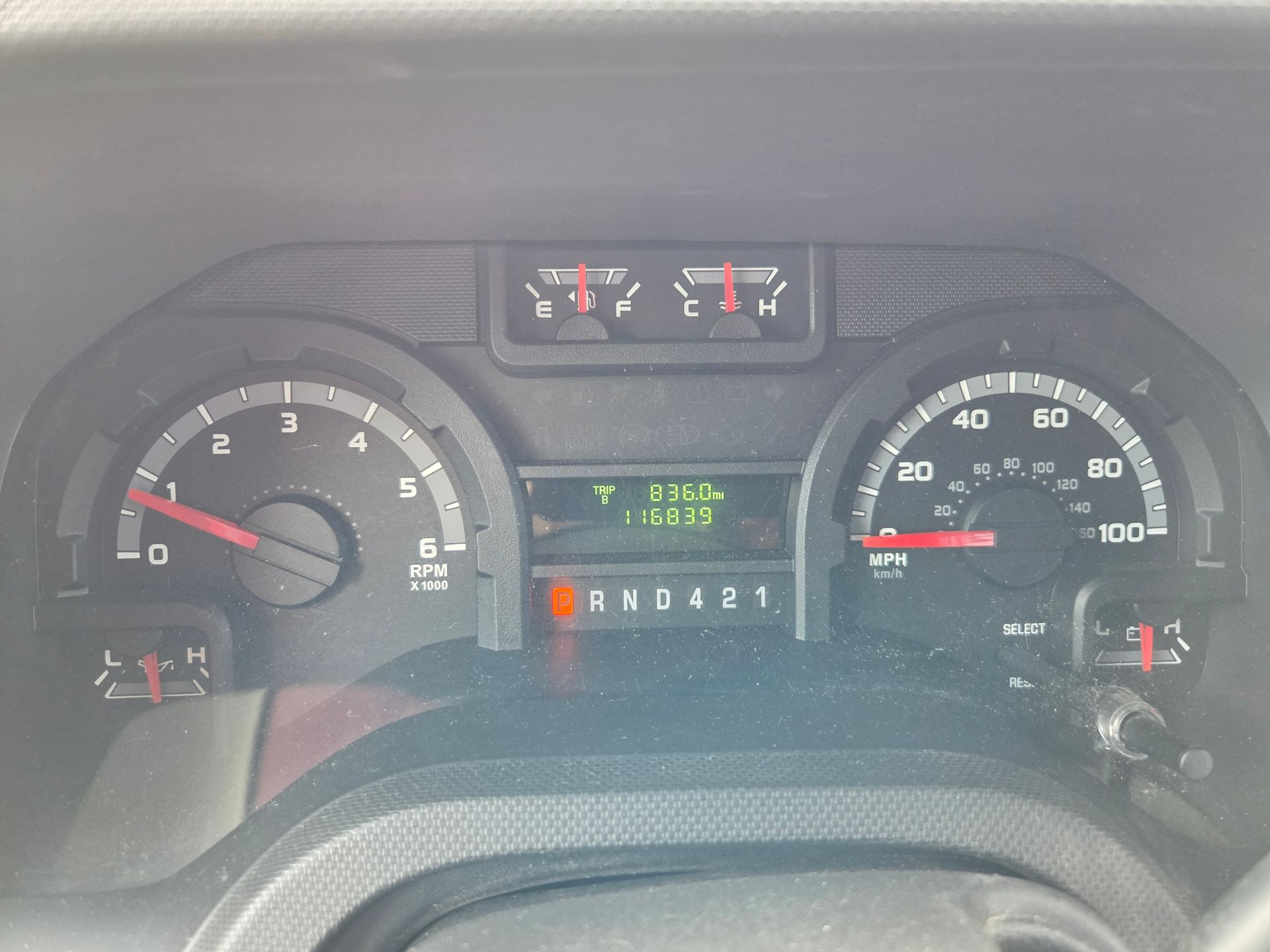 Car dashboard with speedometer, fuel gauge, and digital display showing warning lights.