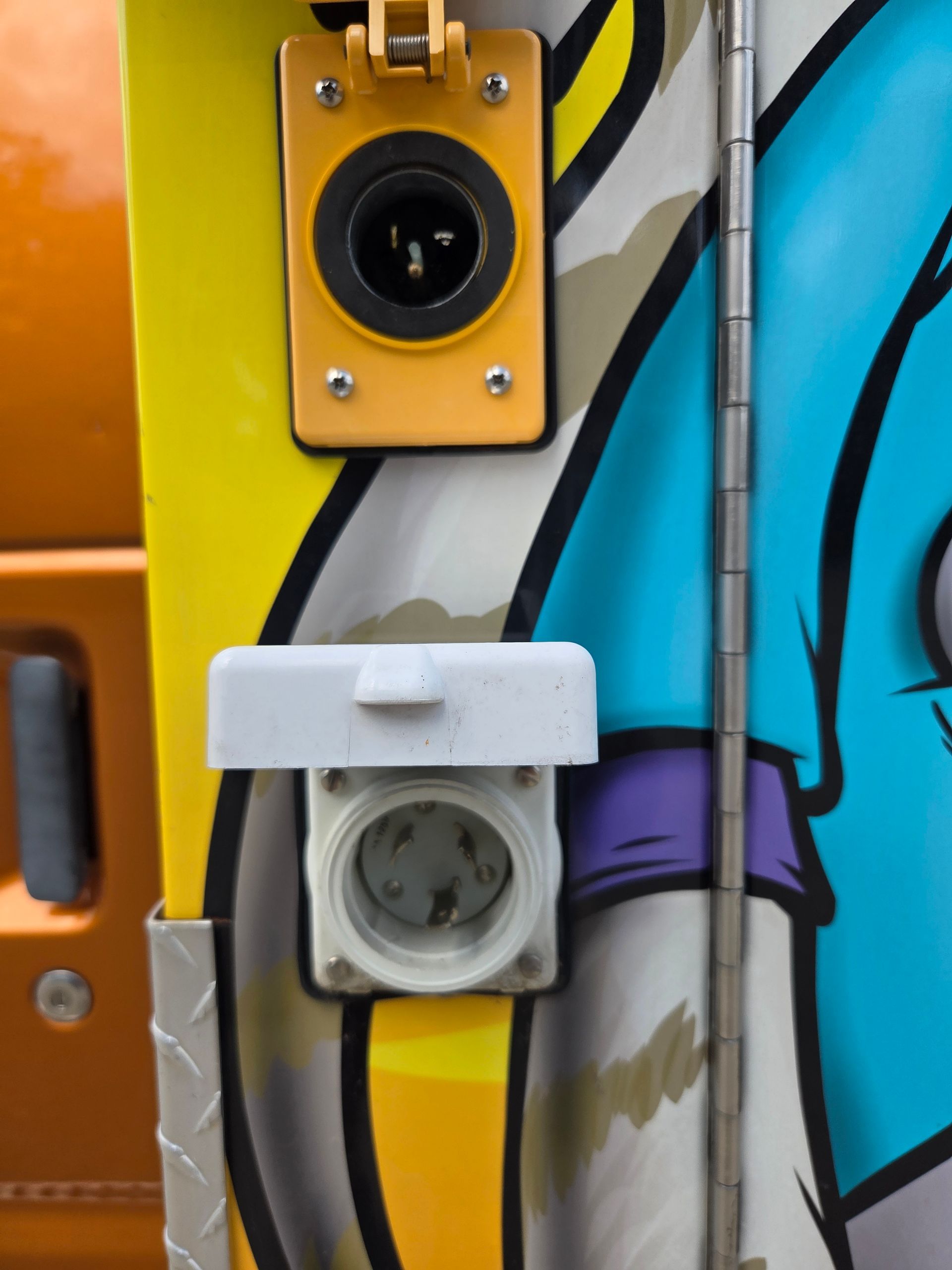 Two wall outlets mounted on a colorful graffiti-covered surface, one yellow and one white.