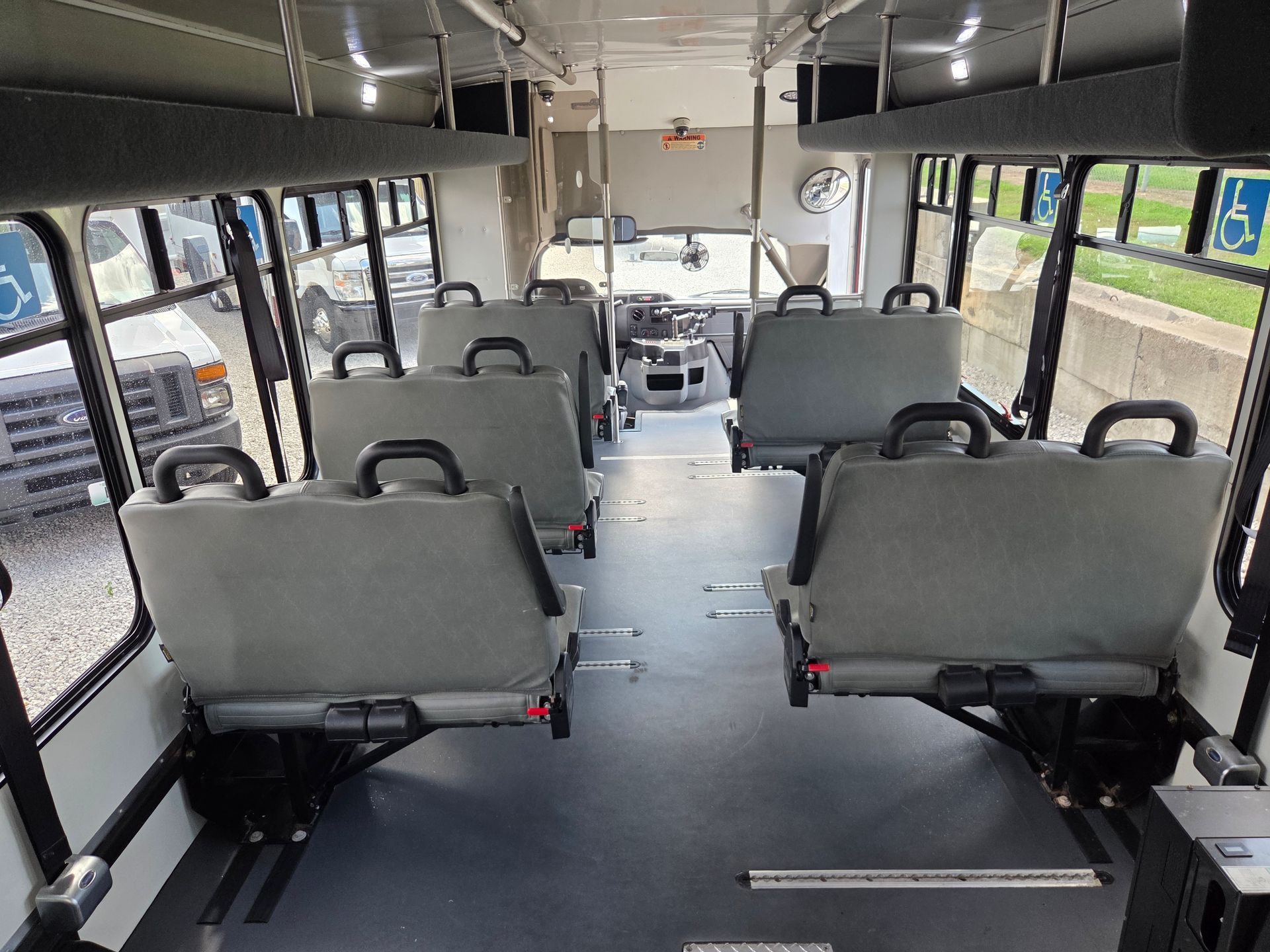 Empty shuttle bus interior with rows of gray seats and large side windows