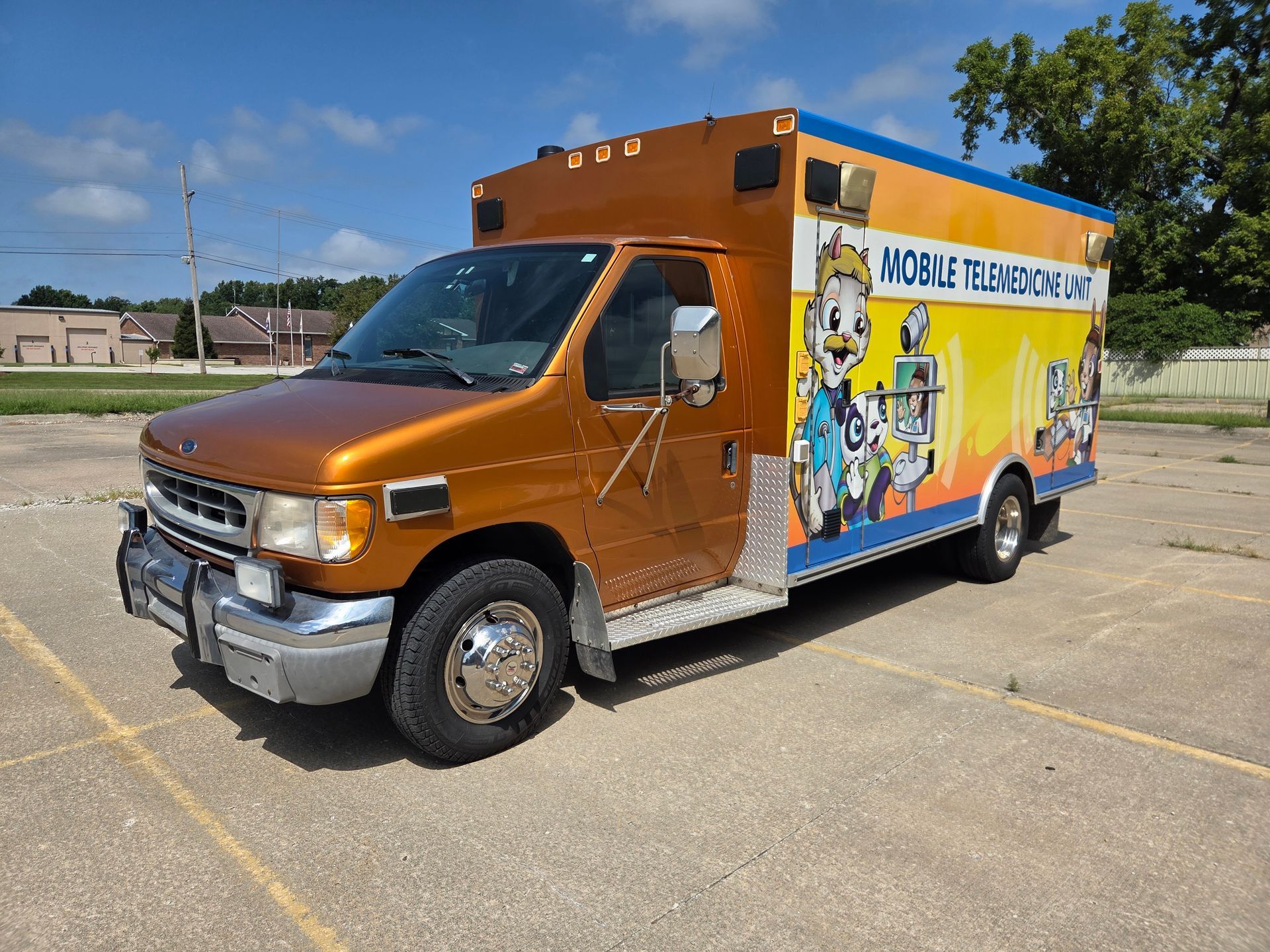 Orange mobile grooming van with colorful pet-themed graphics parked in an empty lot.