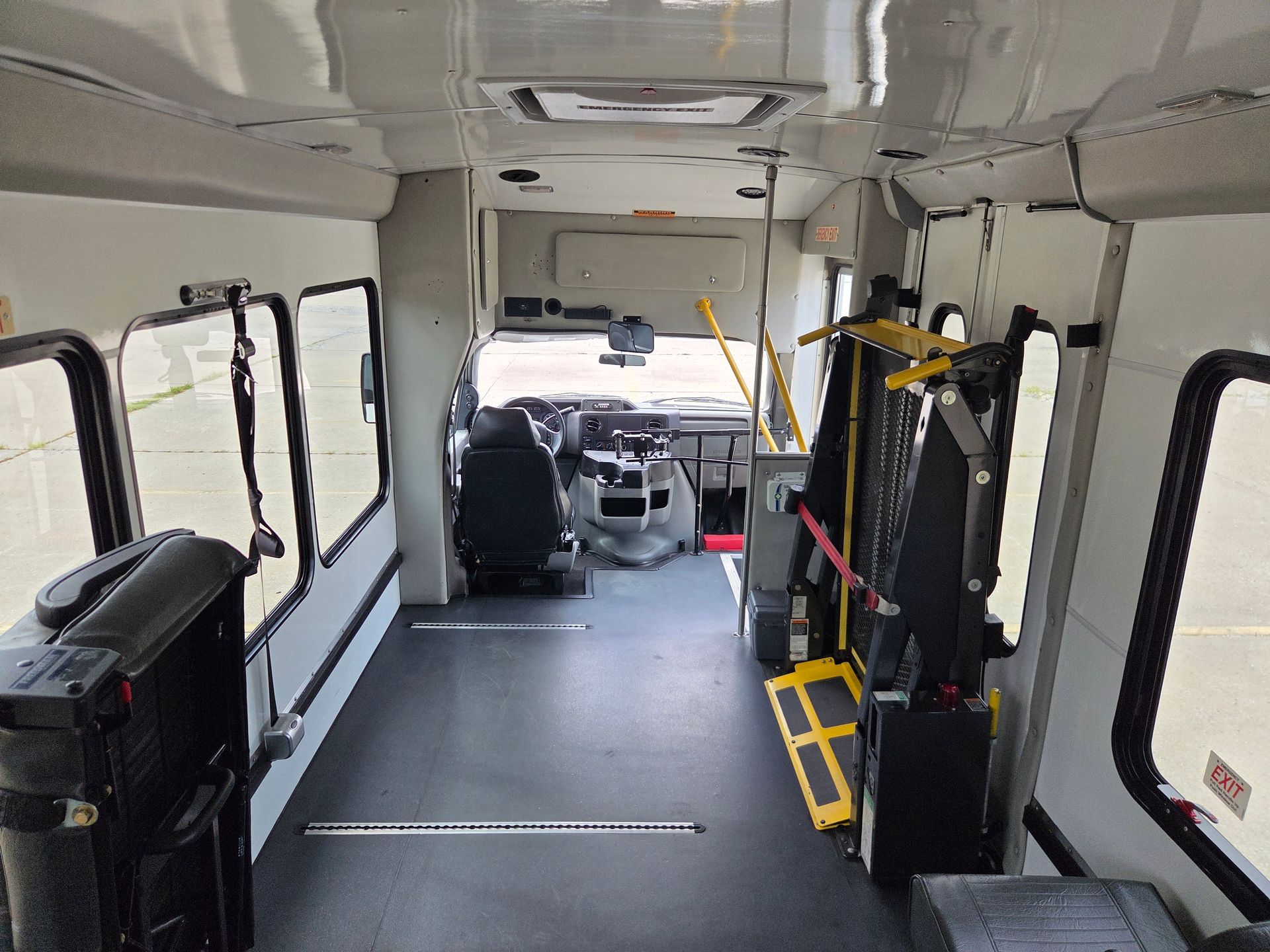 Empty shuttle bus interior with wheelchair lift and black seats near the front door