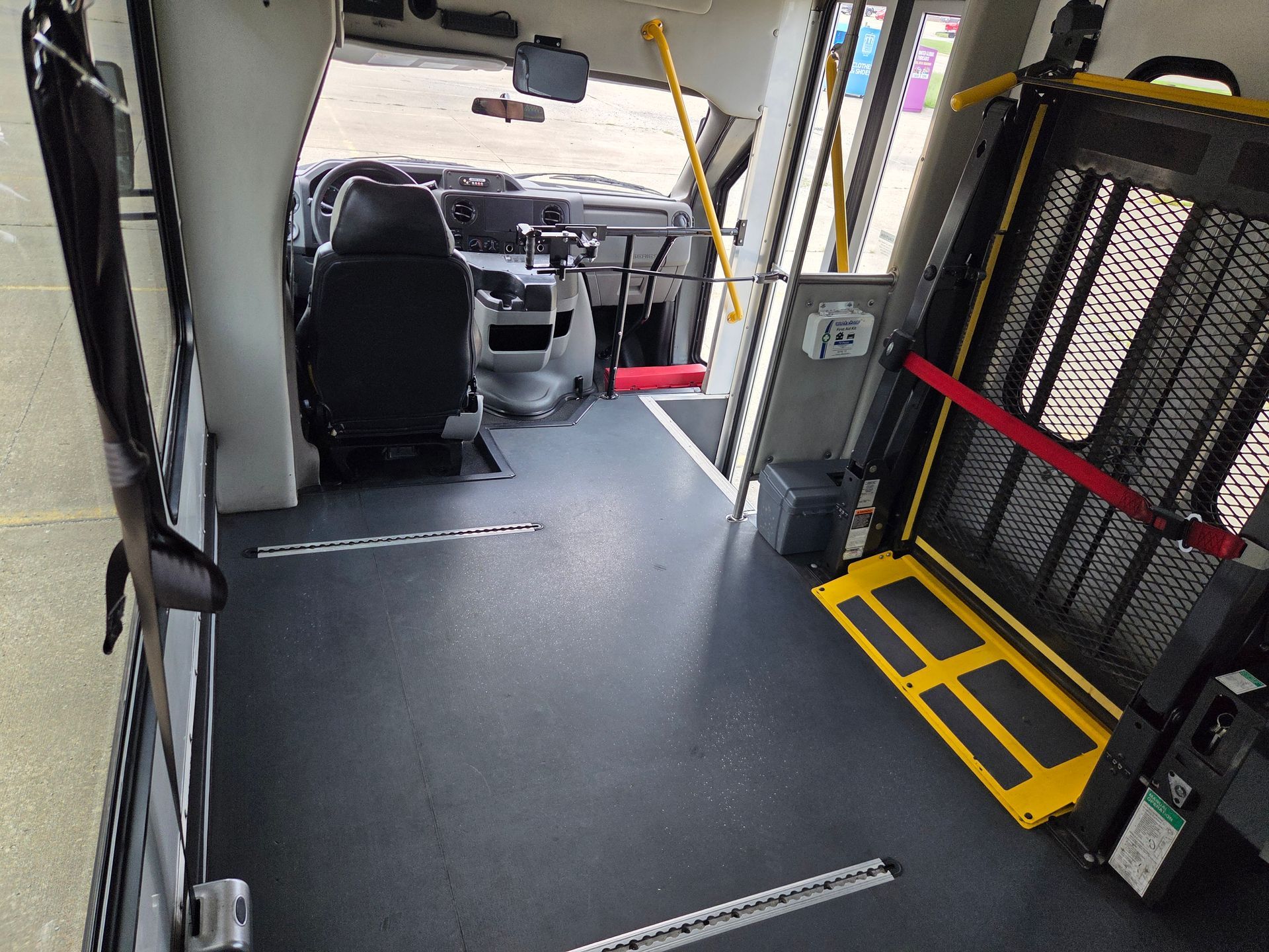 Interior of a wheelchair-accessible shuttle bus with a fold-down ramp and seating area.