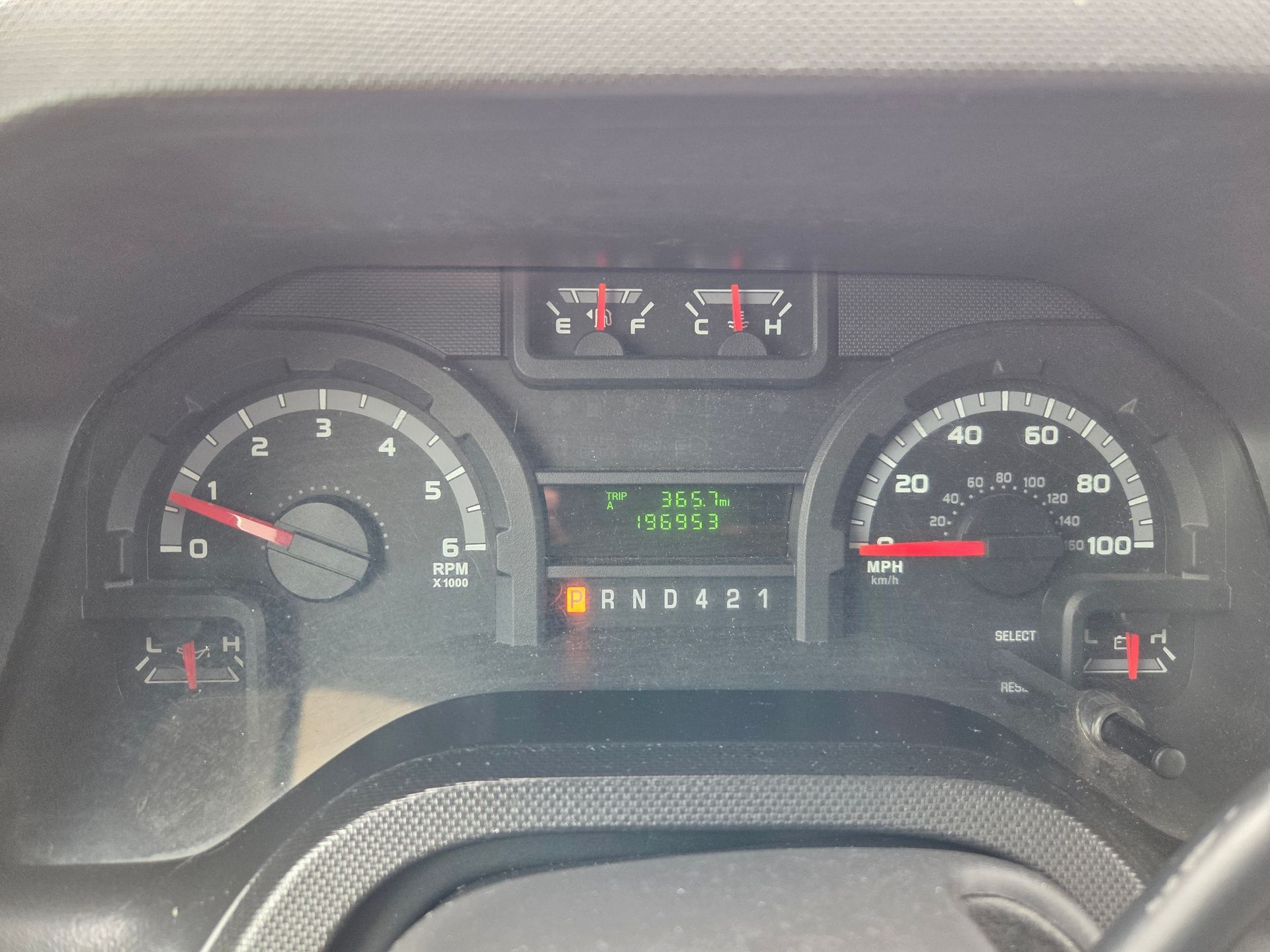 Car dashboard with gauges and warning lights illuminated, speedometer and tachometer visible.