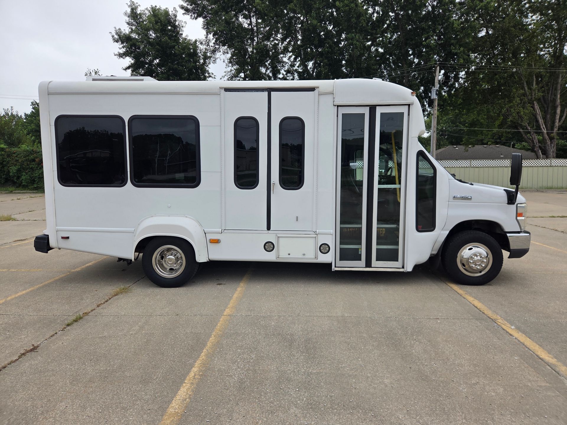 White shuttle bus with a wheelchair lift parked on pavement outdoors.