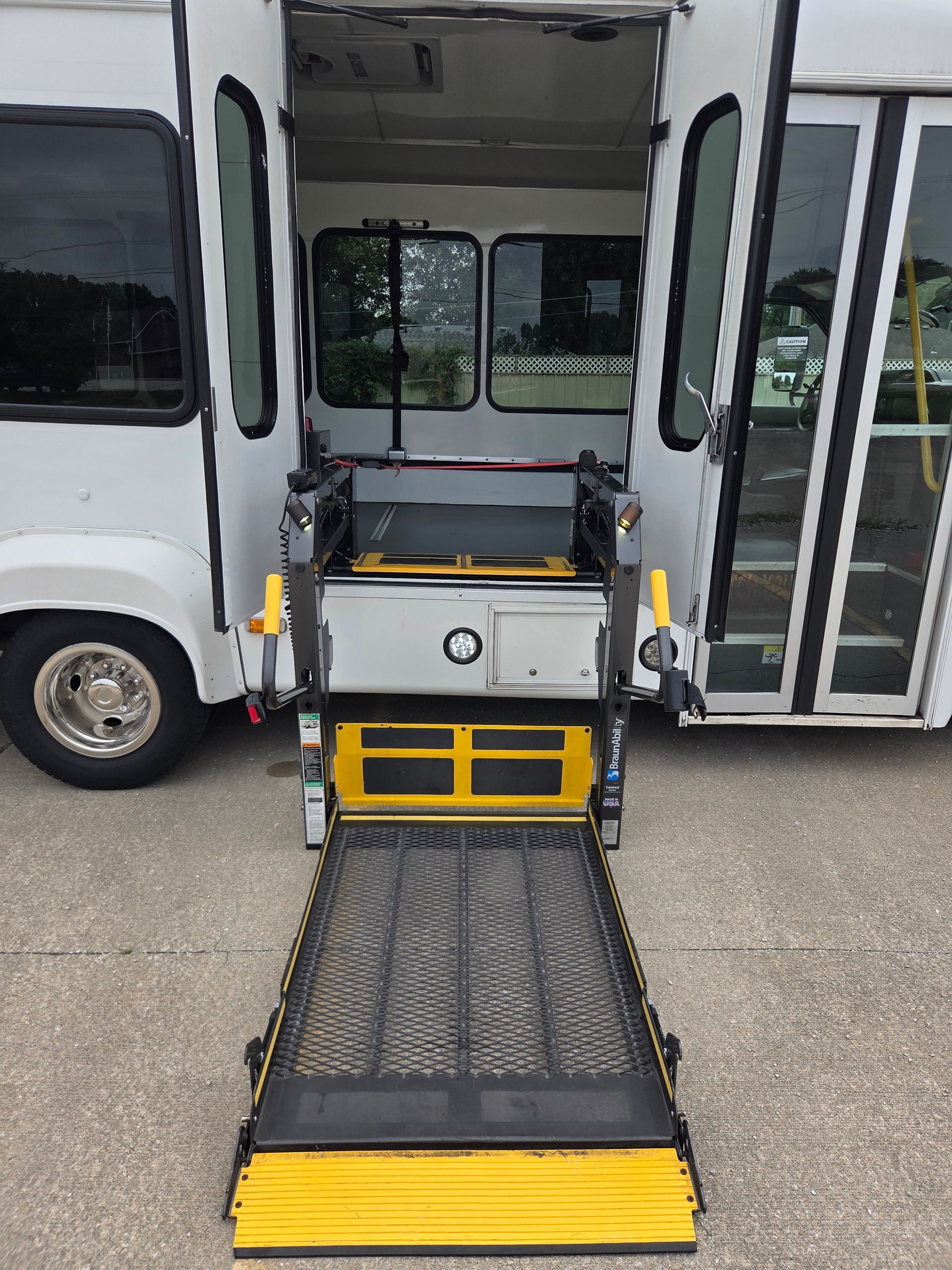 Accessible shuttle bus with deployed wheelchair ramp and open door at curbside