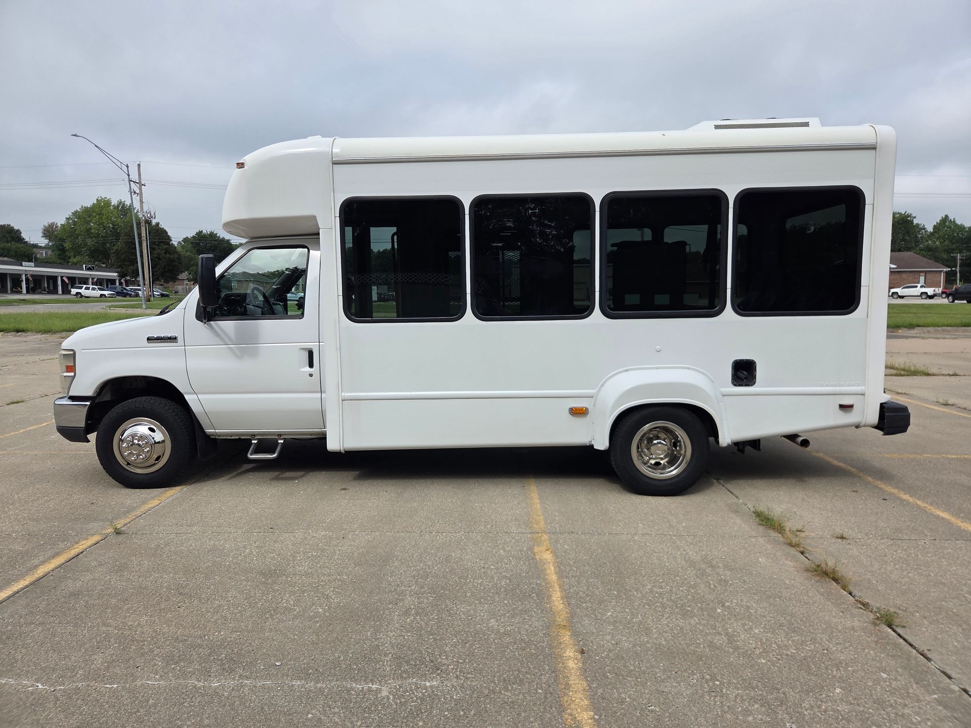White shuttle bus parked in an empty lot on a cloudy day