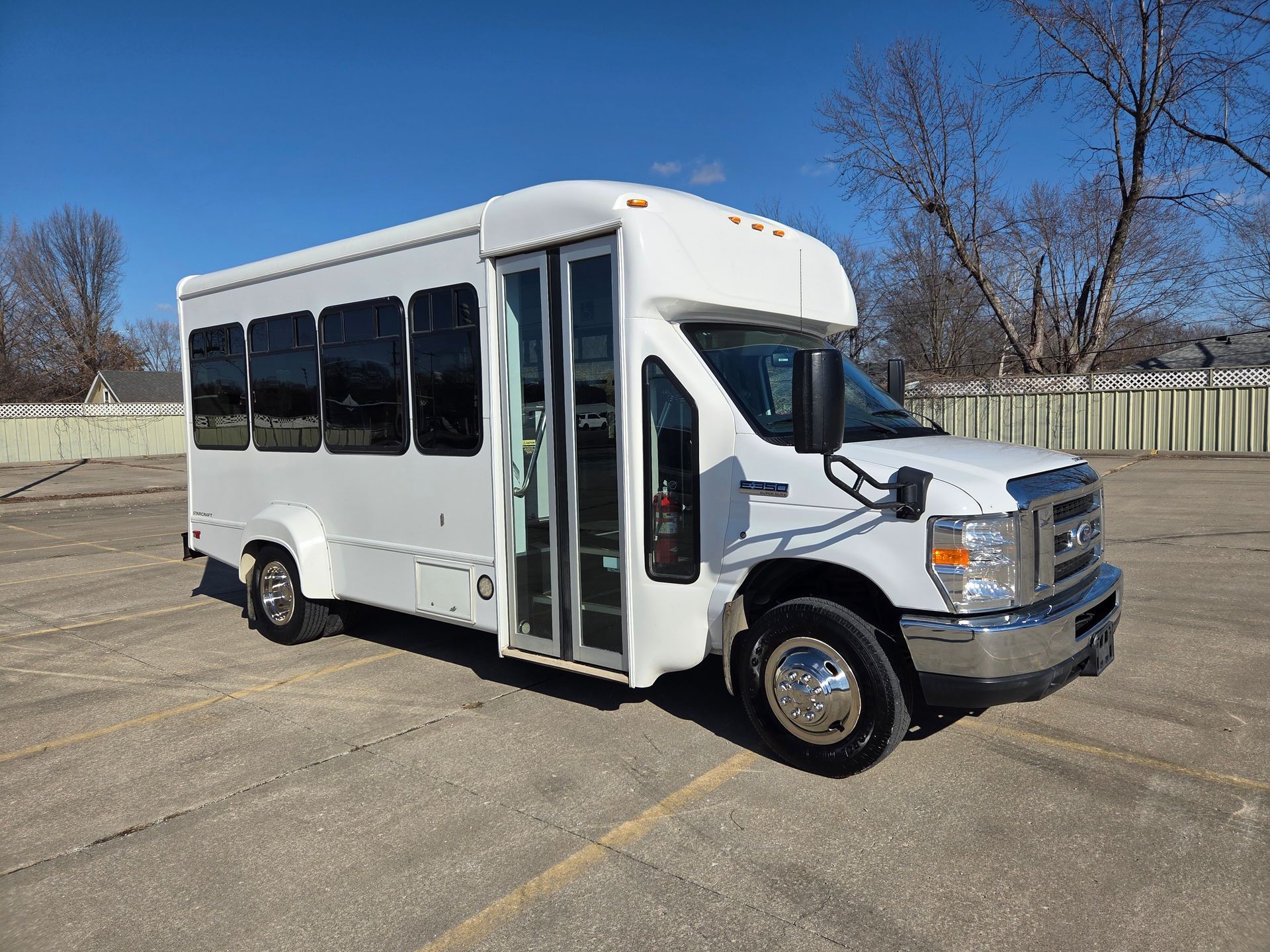 White shuttle bus parked on a concrete lot under a clear blue sky