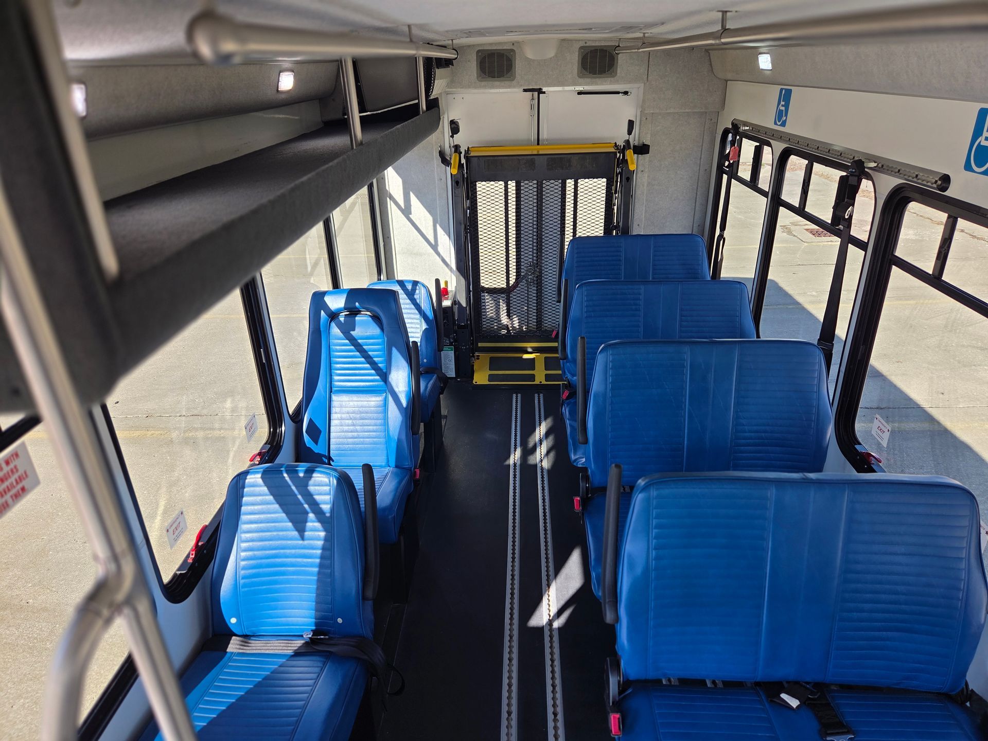 Empty bus interior with blue seats and wheelchair-accessible area near the back