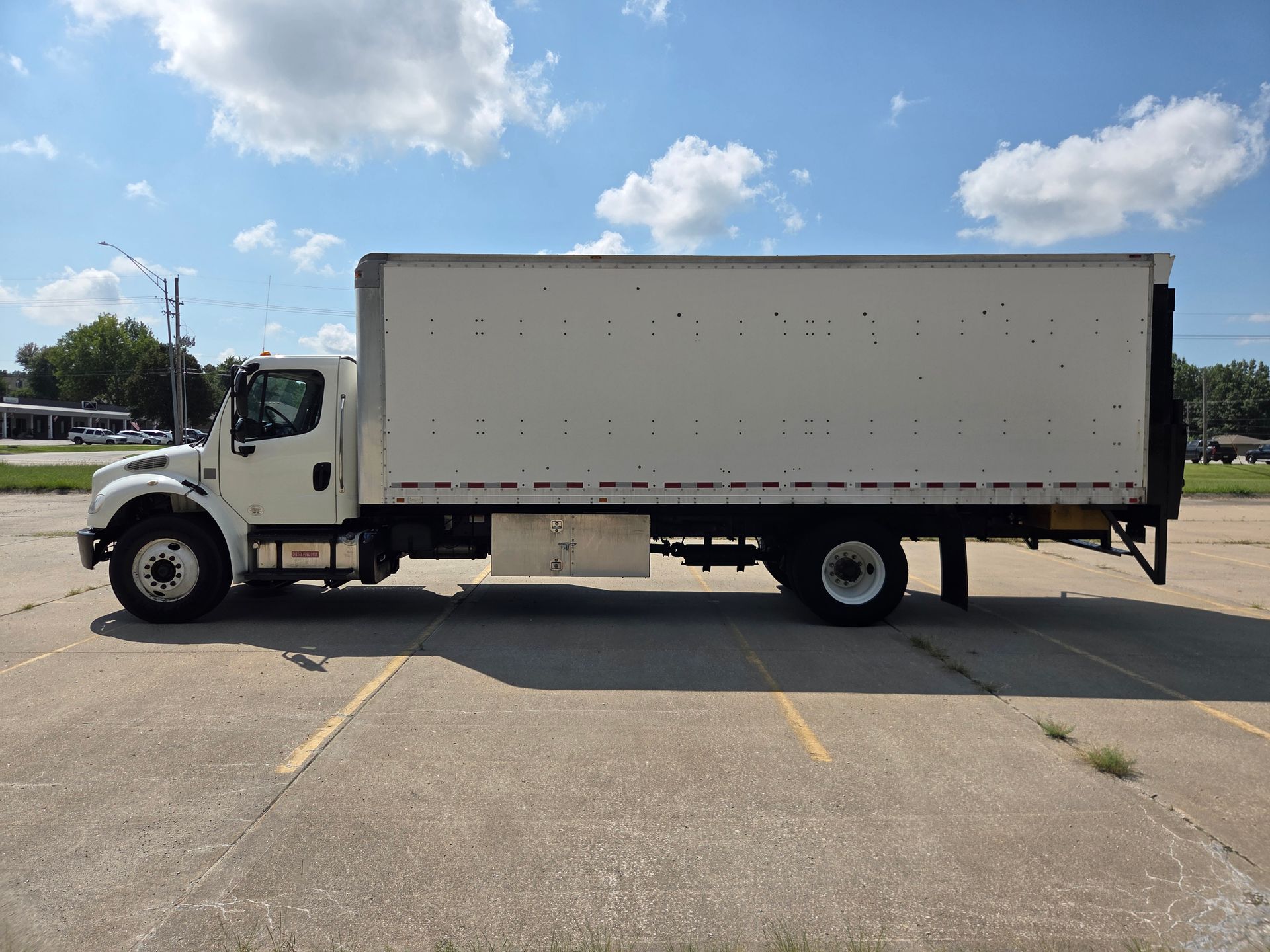 White box truck parked in a lot under a blue sky