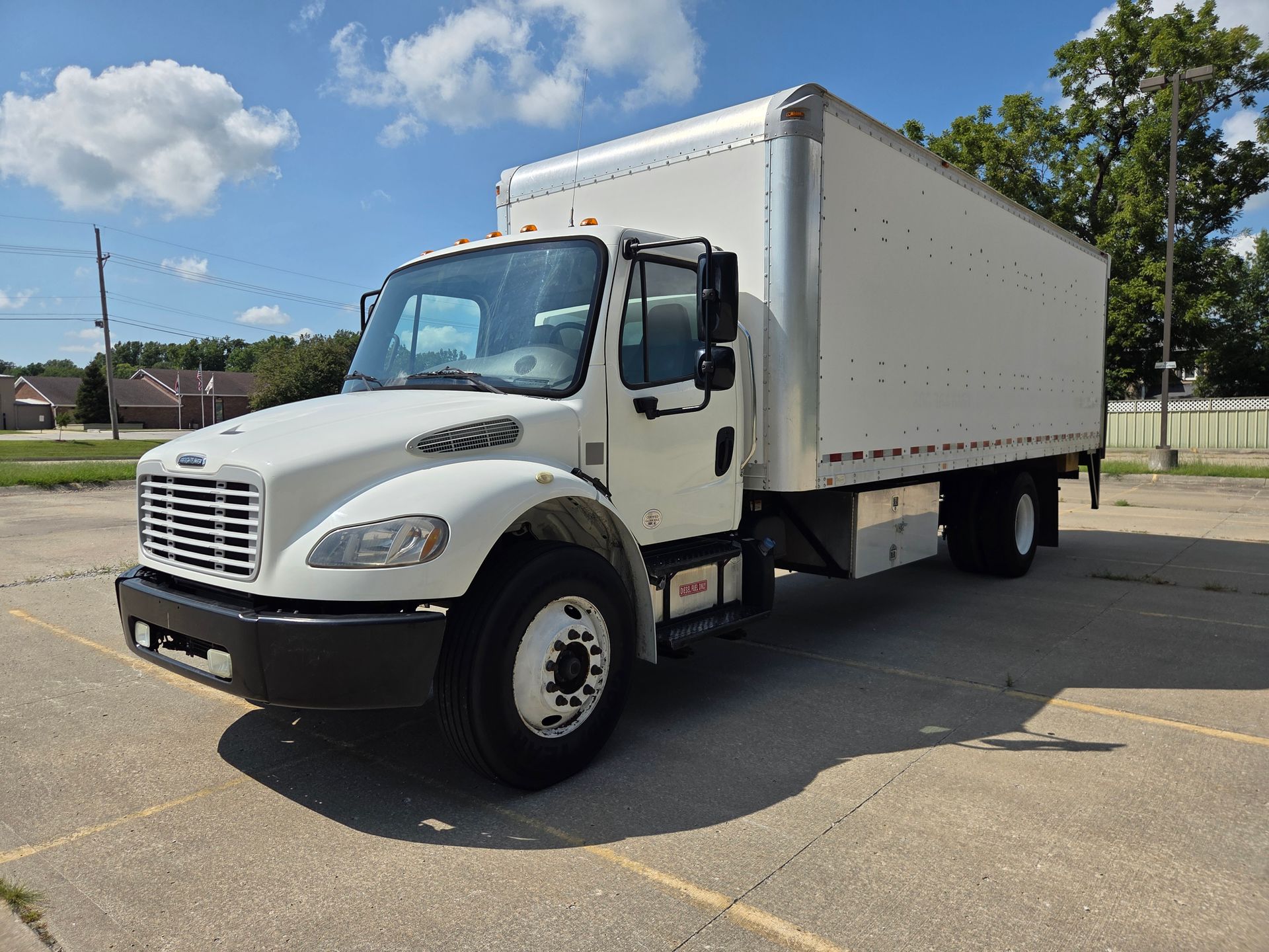 White box truck parked on a sunny lot under a blue sky