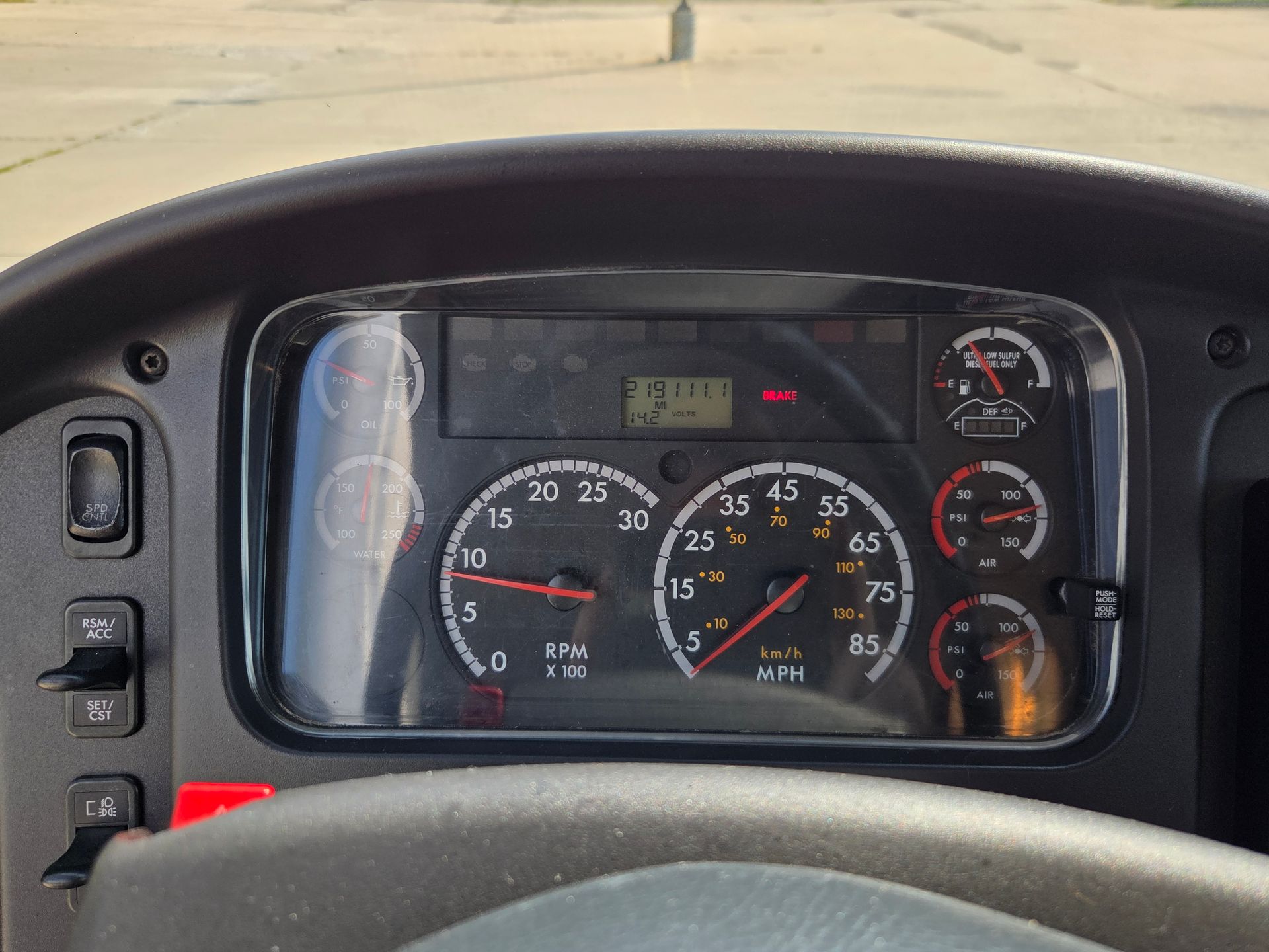 Vehicle dashboard with speedometer and gauges, viewed from the driver’s seat.
