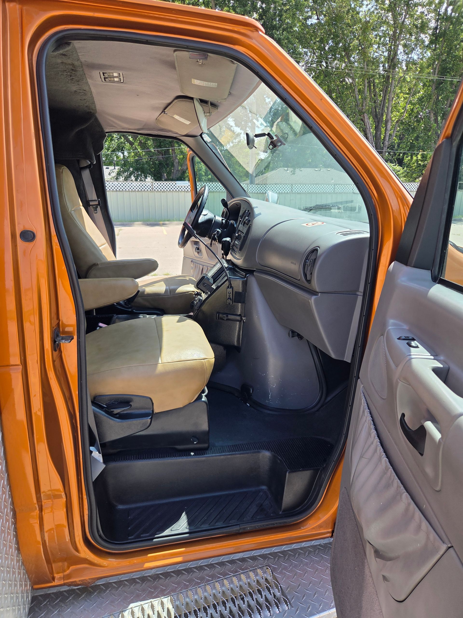 Orange car with open driver’s door, showing beige interior and dashboard.