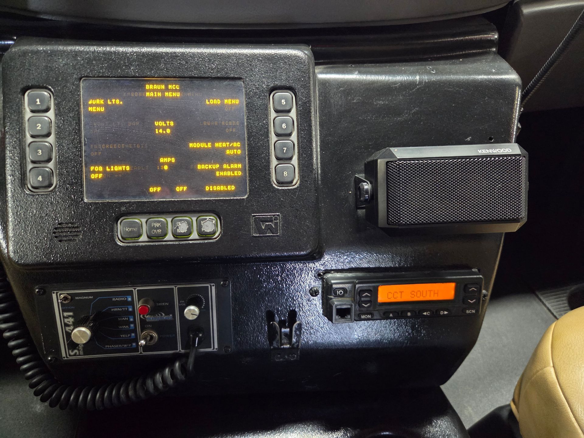 Close-up of a vehicle dashboard with a lit digital display, buttons, and a mounted radio unit.