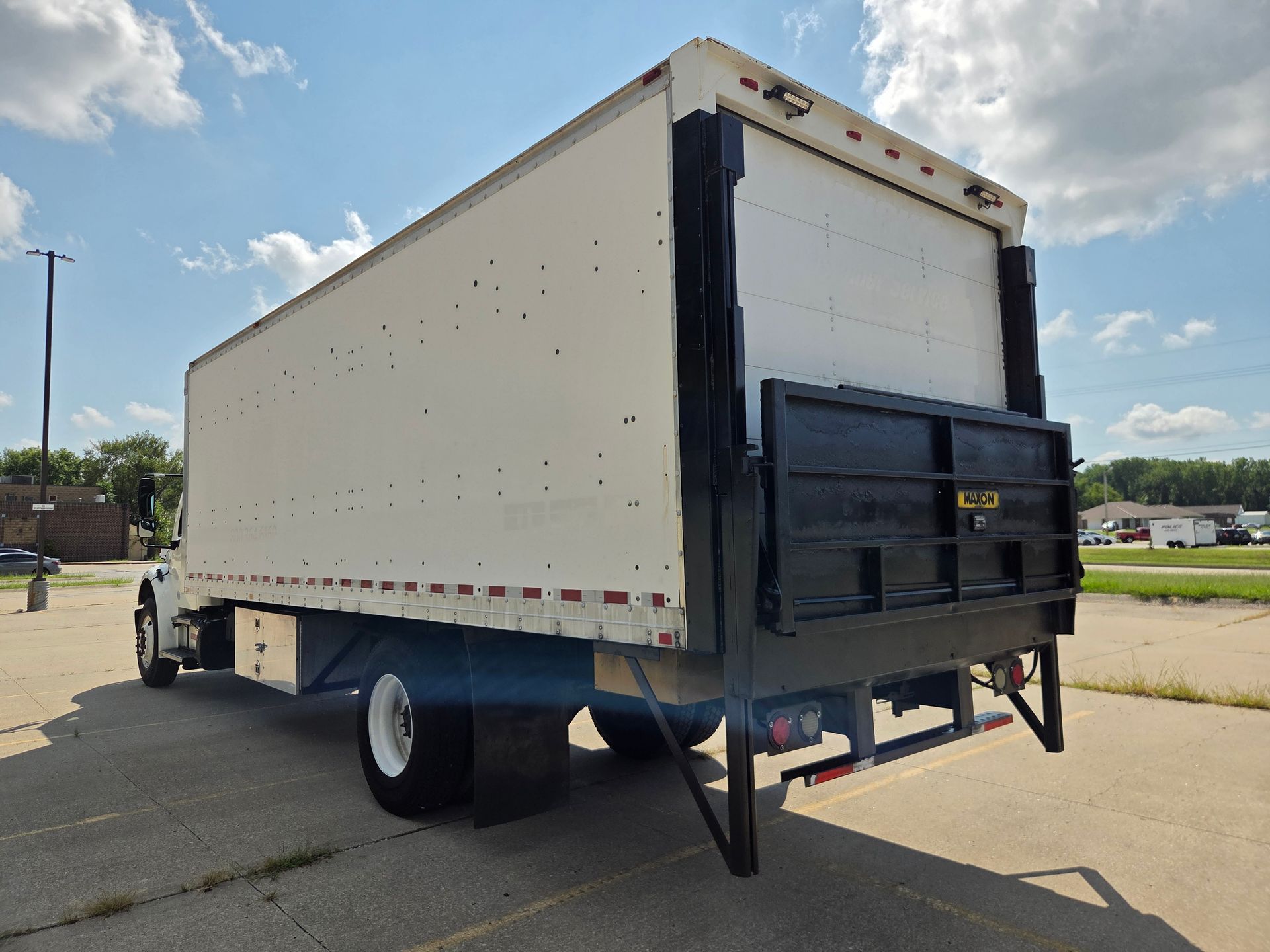 White box truck with rear liftgate parked on a sunny lot