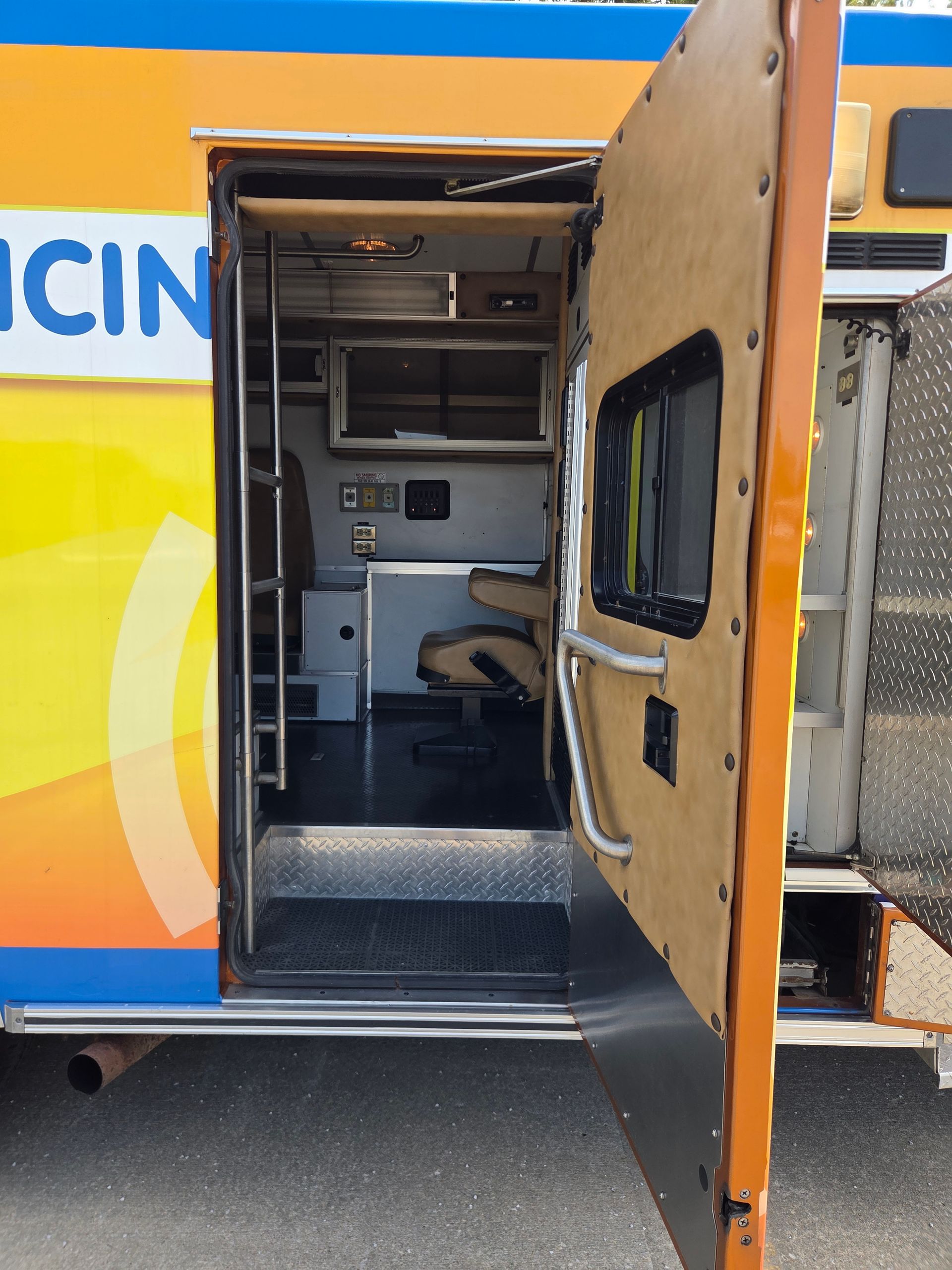 Open ambulance side door showing the interior treatment area with stretcher and equipment.