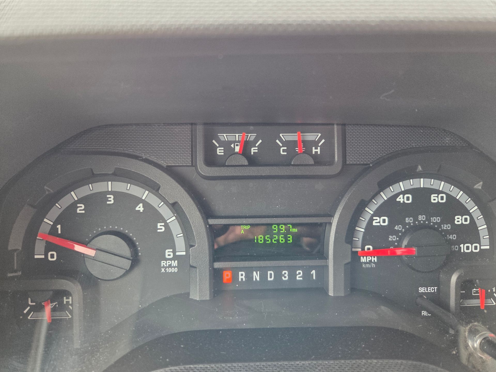 Car dashboard instrument cluster showing speedometer, tachometer, fuel, and temperature gauges, odometer lit green.