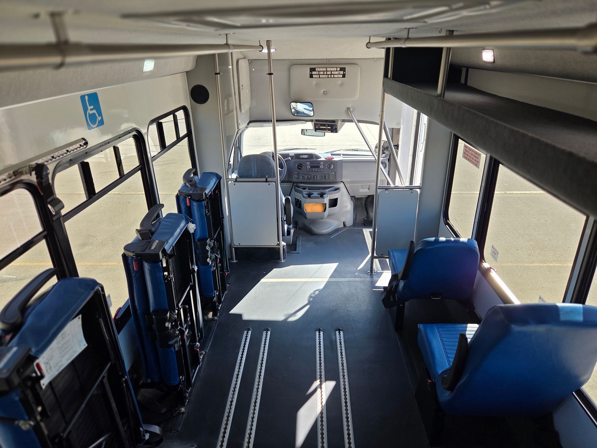 Empty bus interior with blue seats and accessible wheelchair area near the front door.
