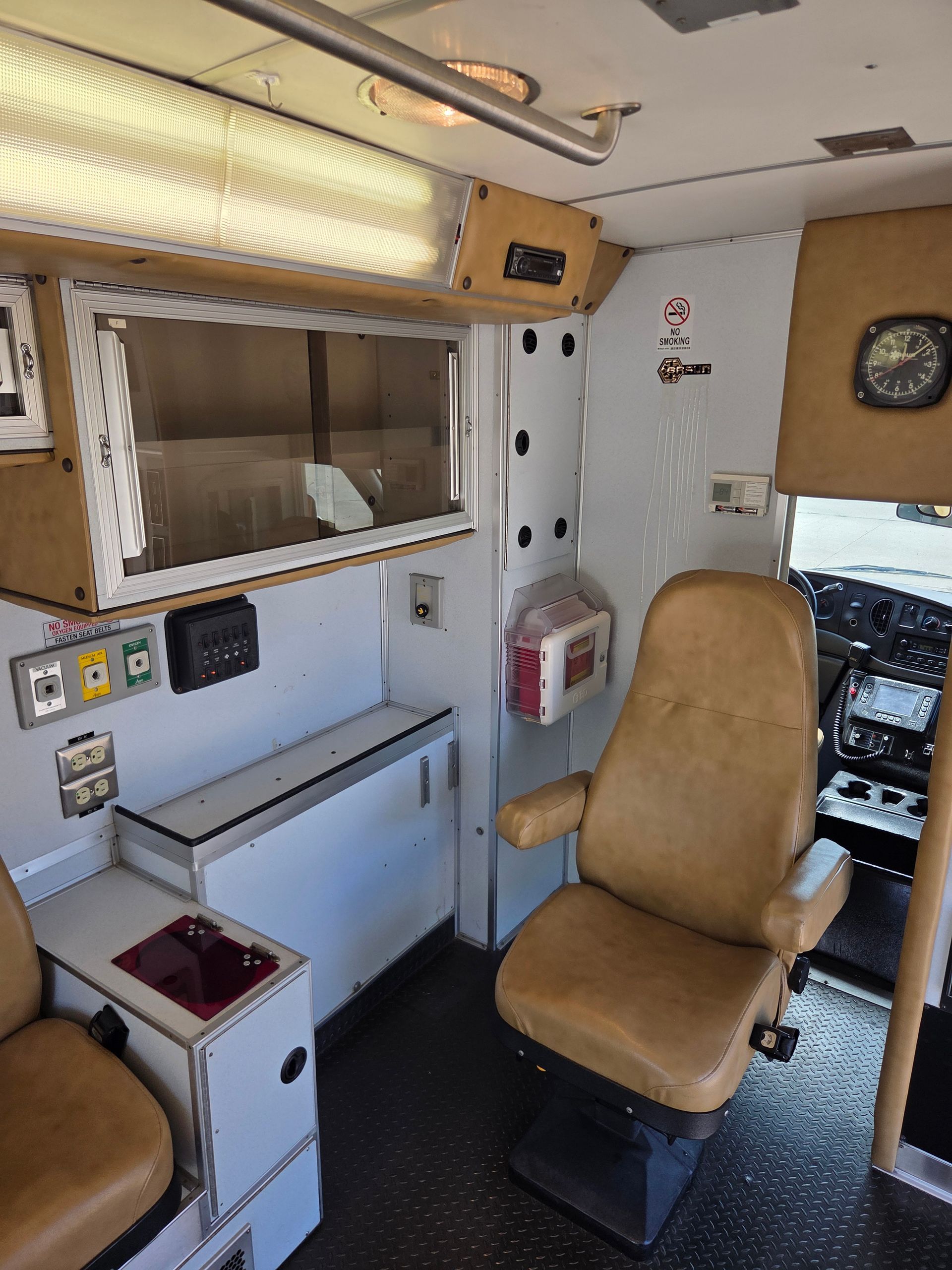 Compact cabin interior with tan chair, cabinets, mirror, and overhead storage in a vehicle or RV.