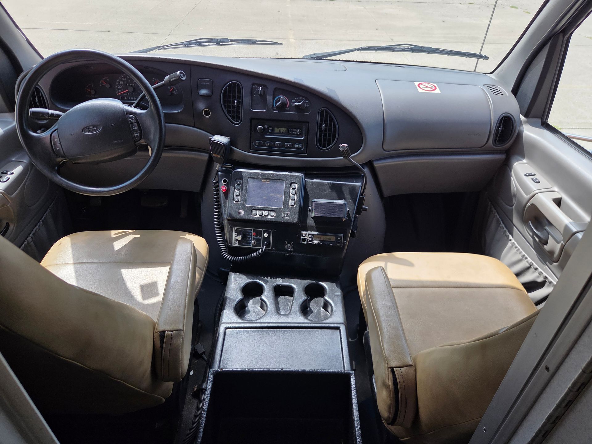 Front view of a car interior with tan seats, black dashboard, and center console with cup holders