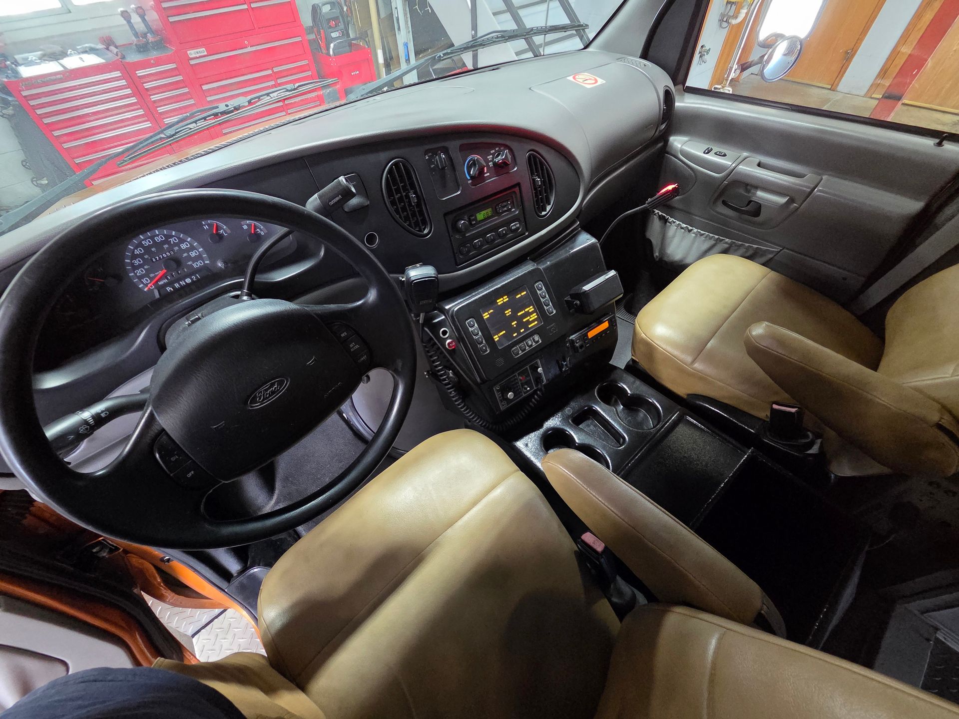 Car interior with black dashboard, tan seats, steering wheel, and center console viewed from the front seats